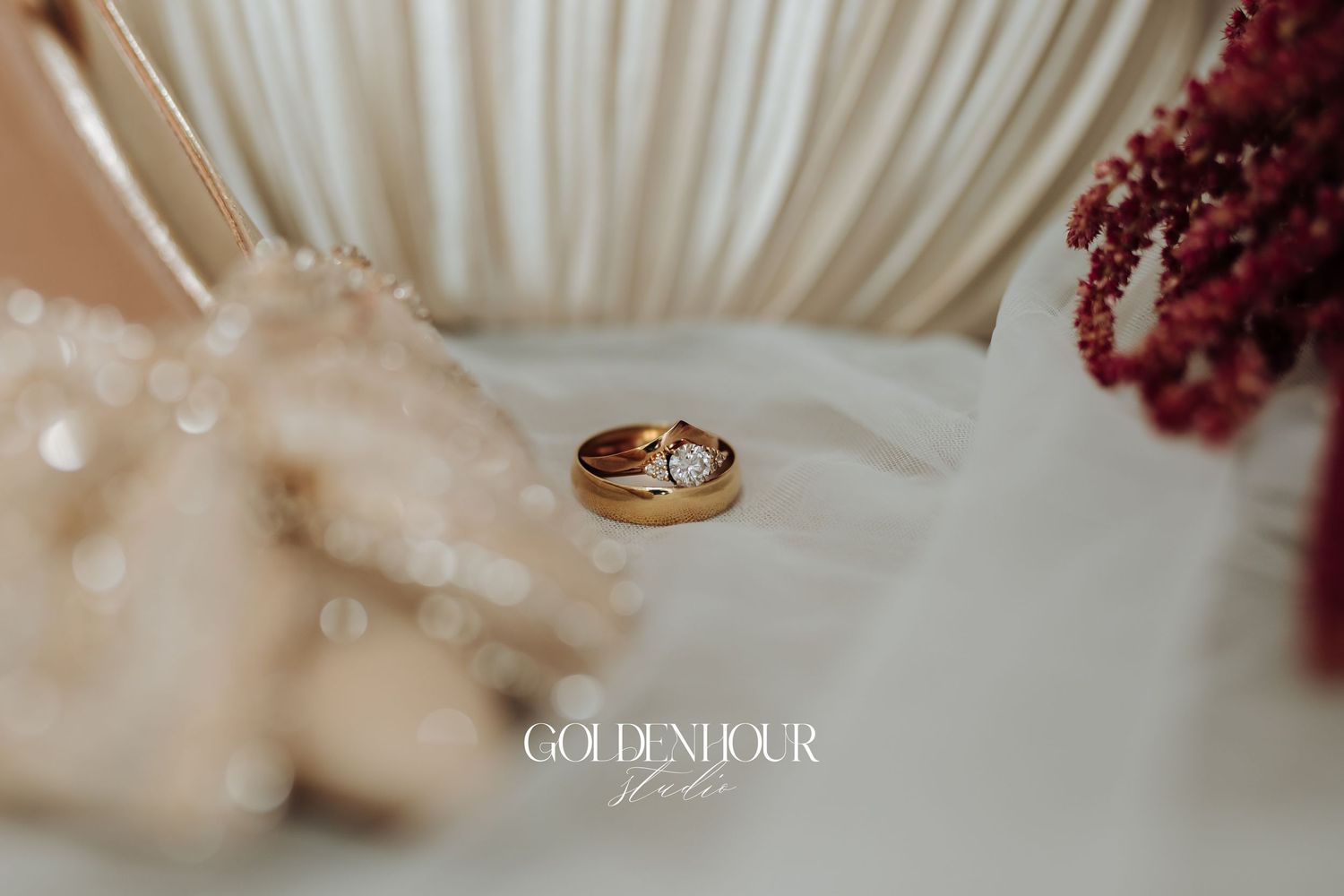Wedding rings and floral decor create an elegant arrangement against a white backdrop with soft lighting.