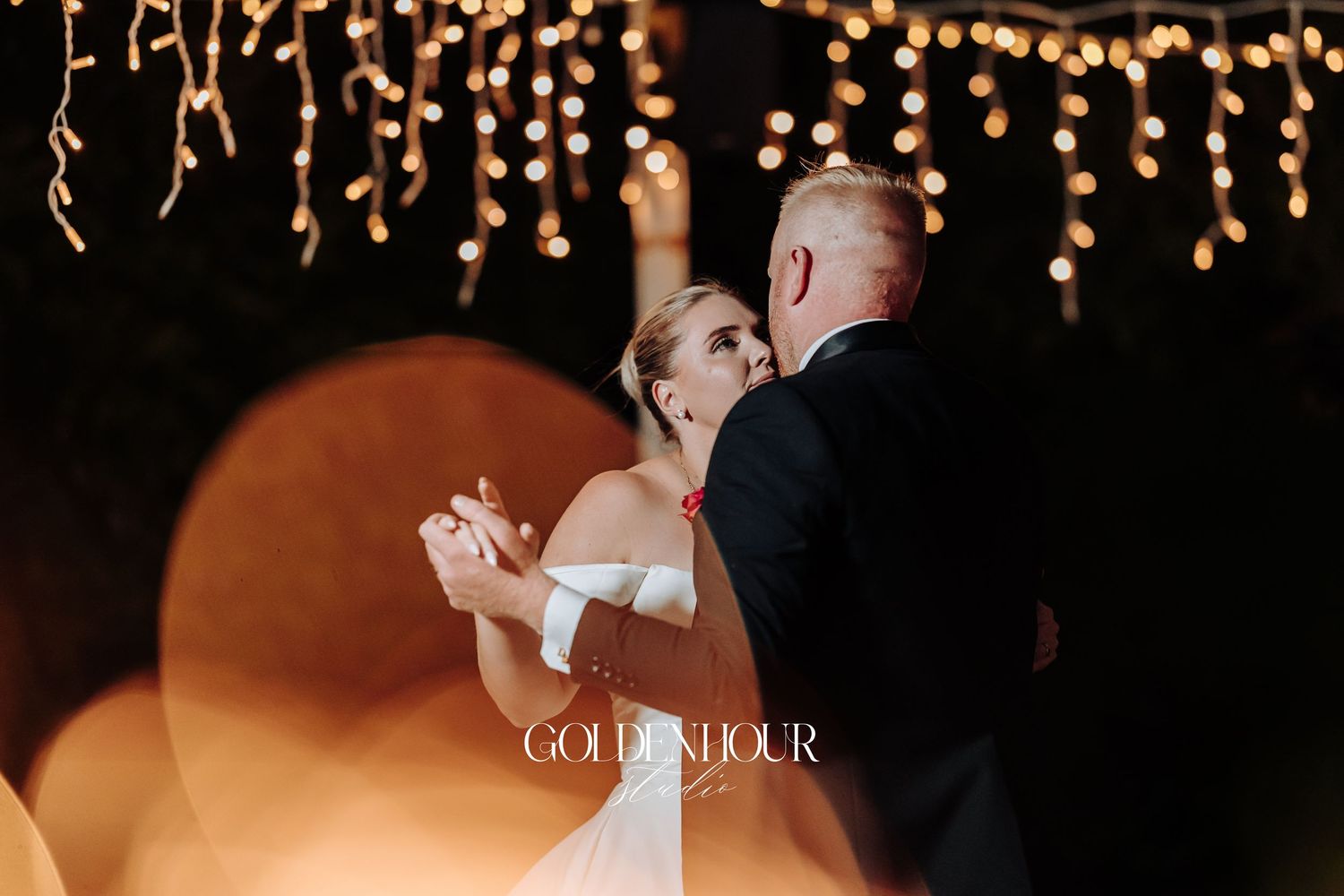 A romantic wedding reception venue decorated with warm glowing string lights and candles creating an intimate atmosphere.