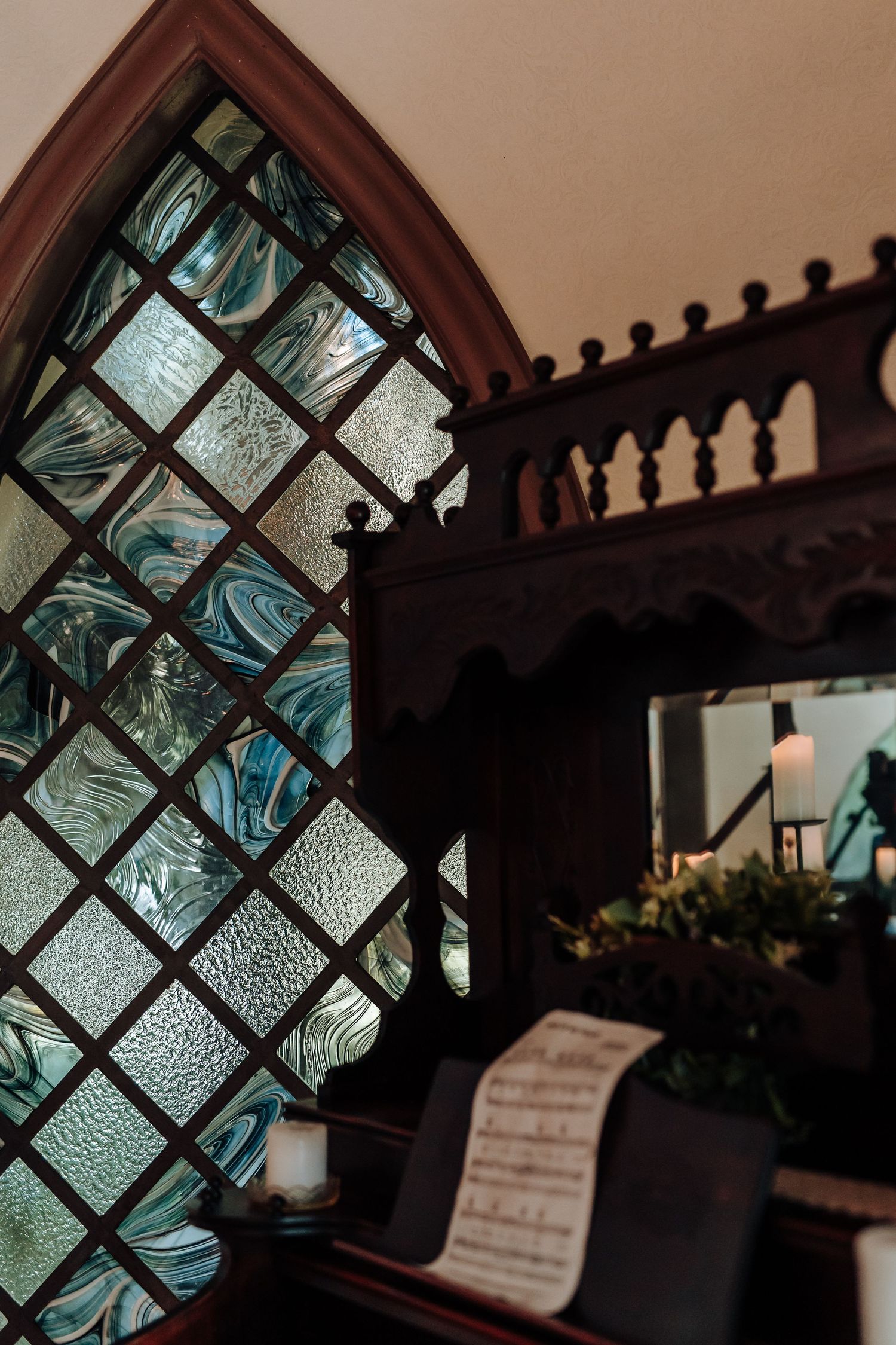 Ornate church window with blue stained glass and decorative metal lattice creates a dramatic silhouette against warm light.