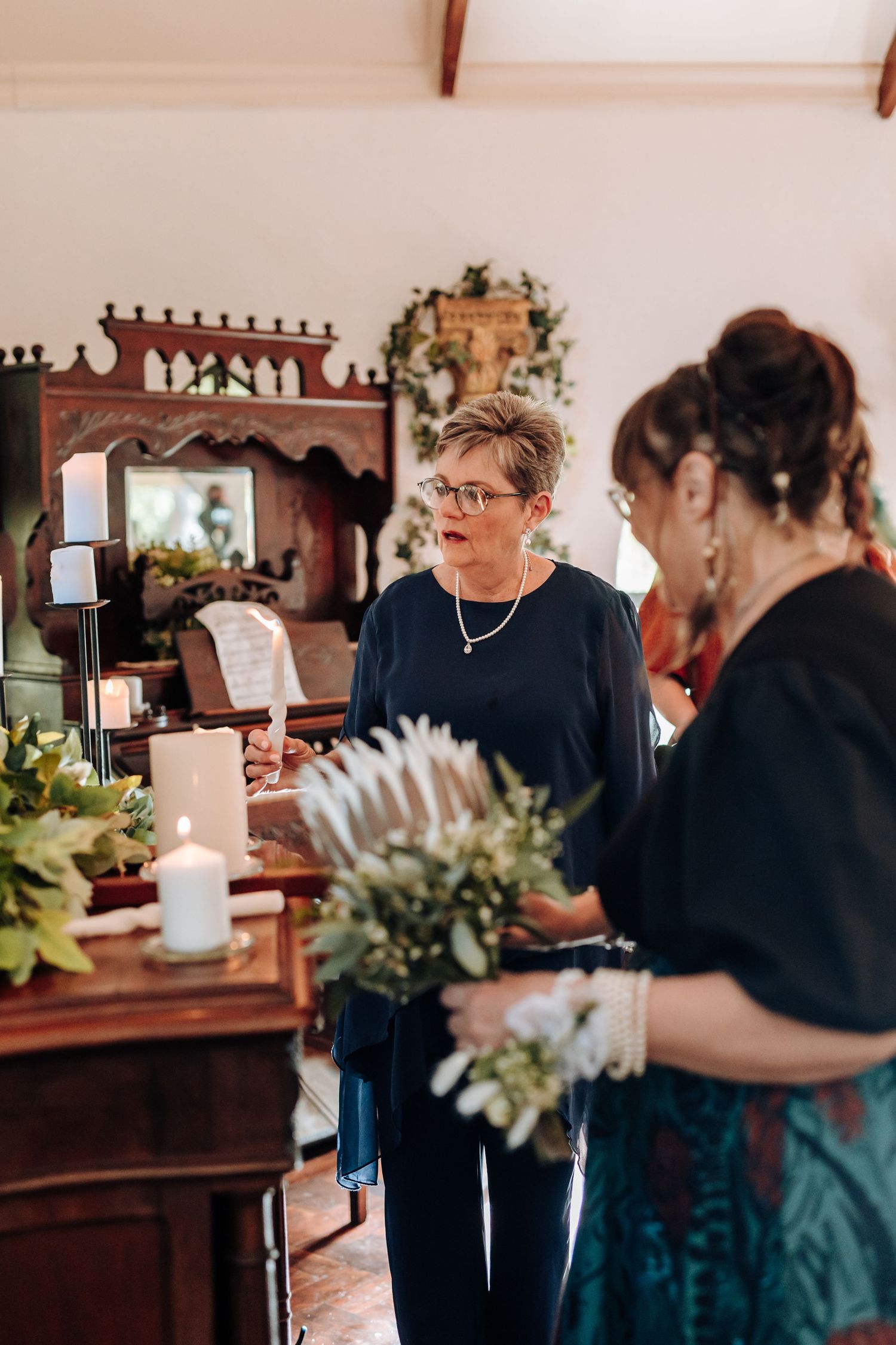 People gather in a dimly lit room with candles and floral decorations for a special event.