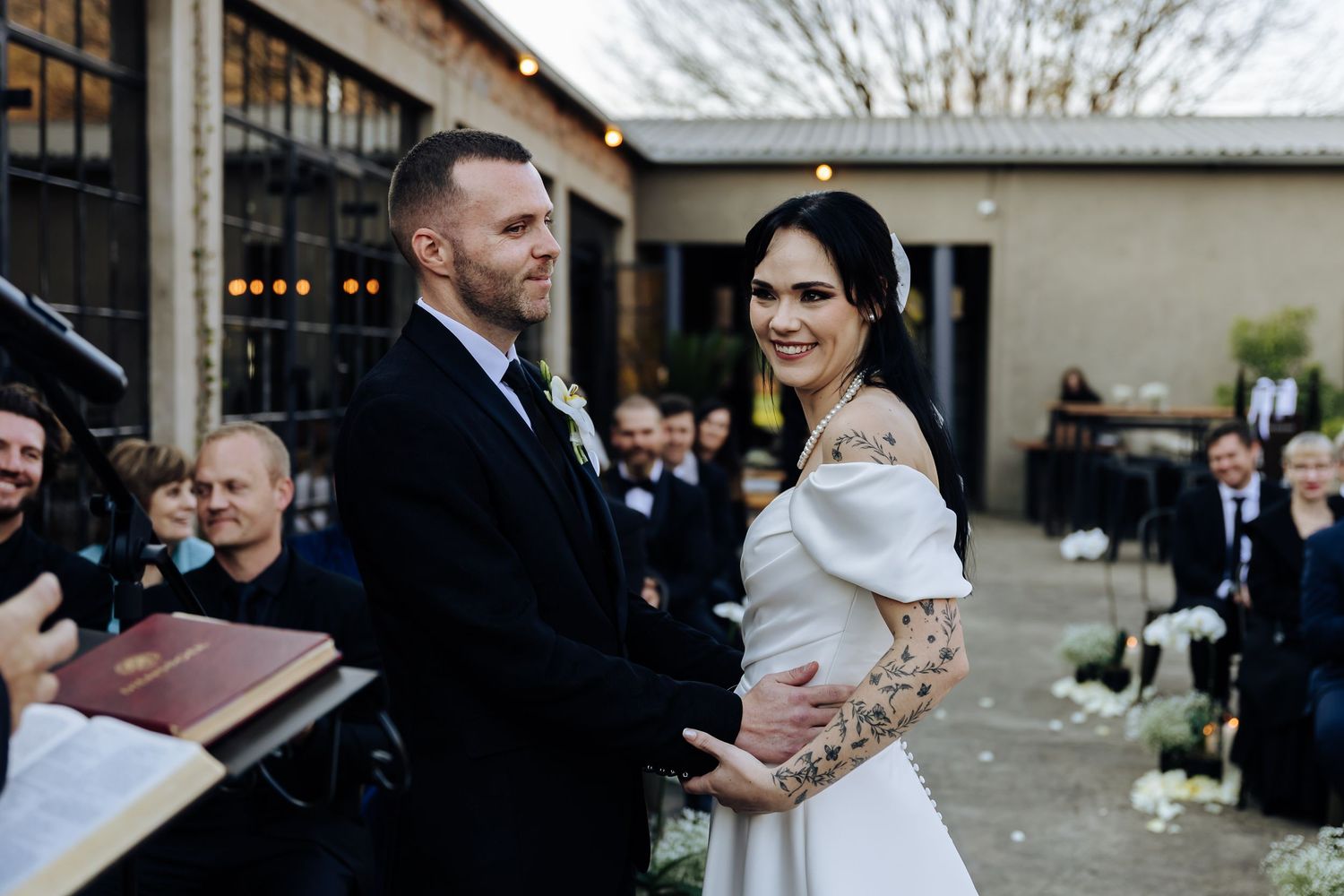 A couple shares a sweet moment together during their outdoor winter wedding ceremony as guests watch from the sides.
