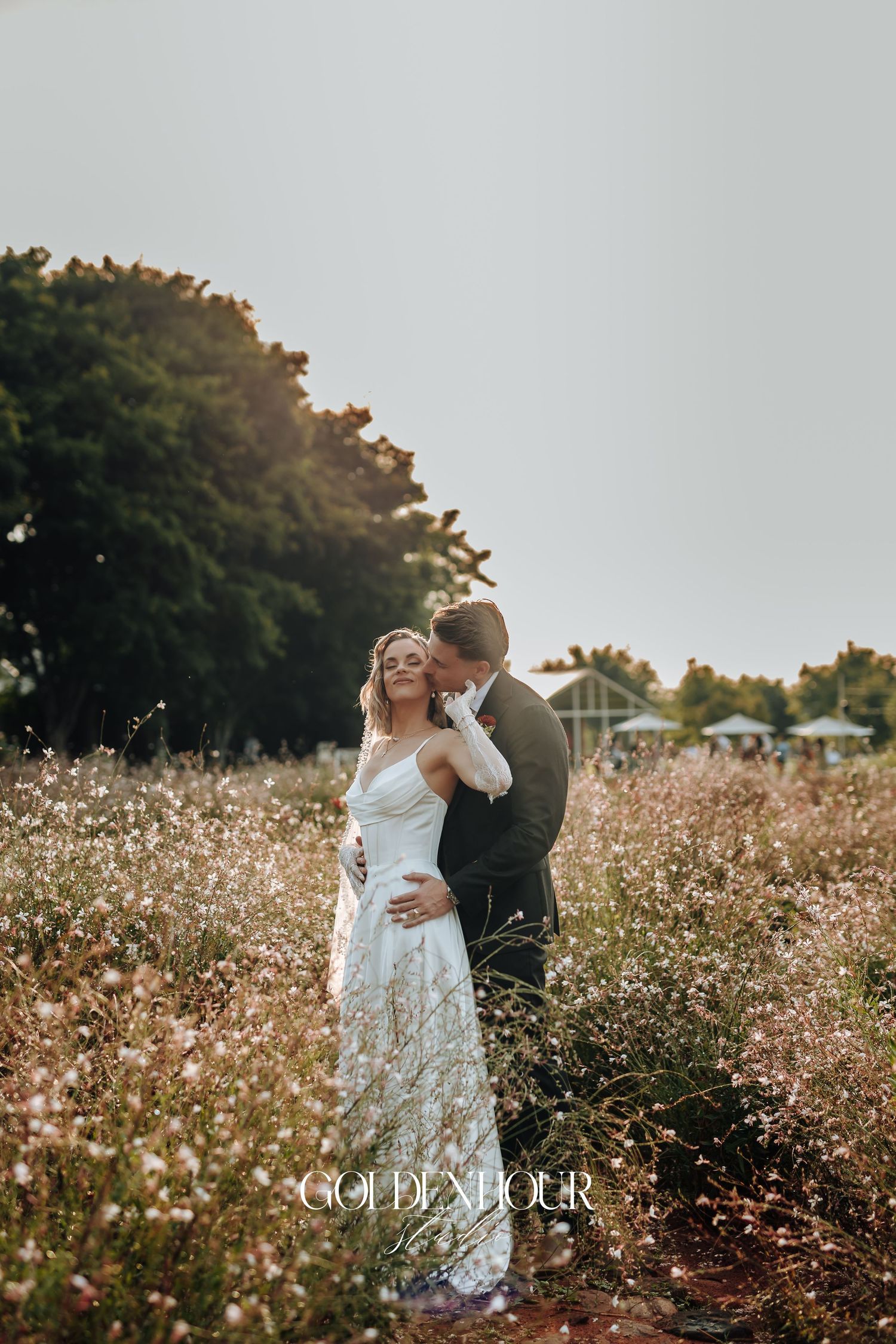 Romantic couple embracing in a field of wildflowers during sunset wedding photos.