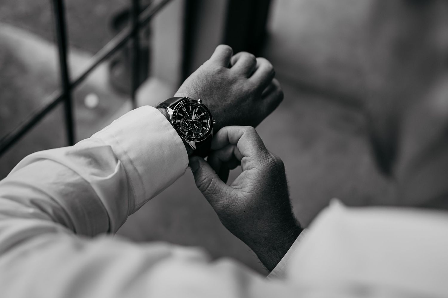Black and white close-up photo showing hands holding a small object with a delicate, focused gesture.