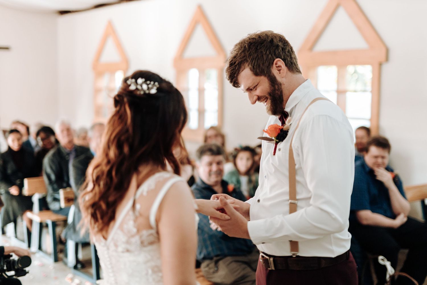 Intimate wedding ceremony moment with guests seated in background of white chapel.