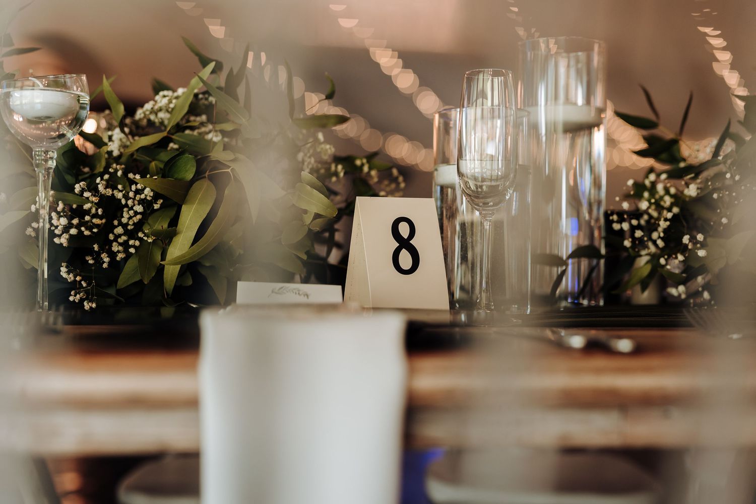 Elegant table centerpiece with table number eight and crystal glassware for wedding reception.