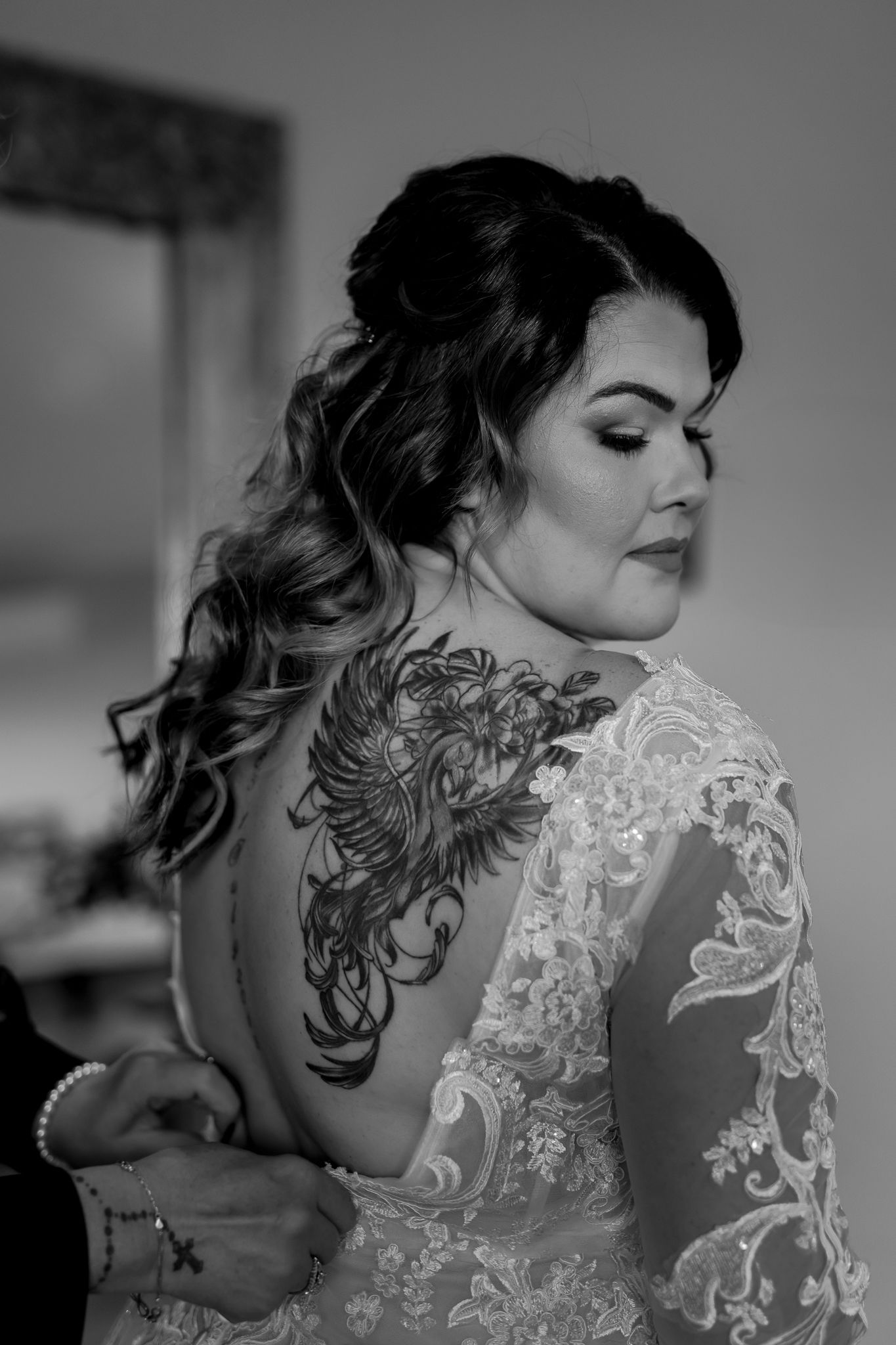 Black and white portrait showing detailed lace dress and ornate tattoo artwork.