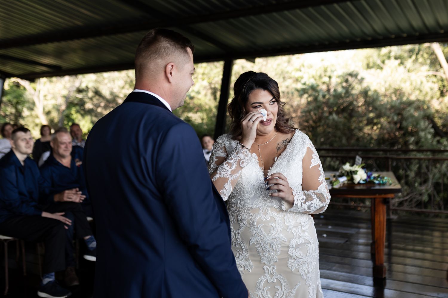 Emotional moment between couple during ring exchange at outdoor wedding ceremony.