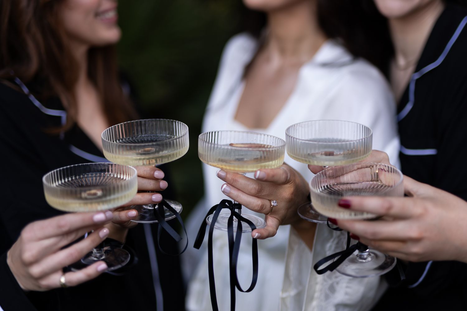 Close-up of hands holding champagne coupes during wedding celebration.