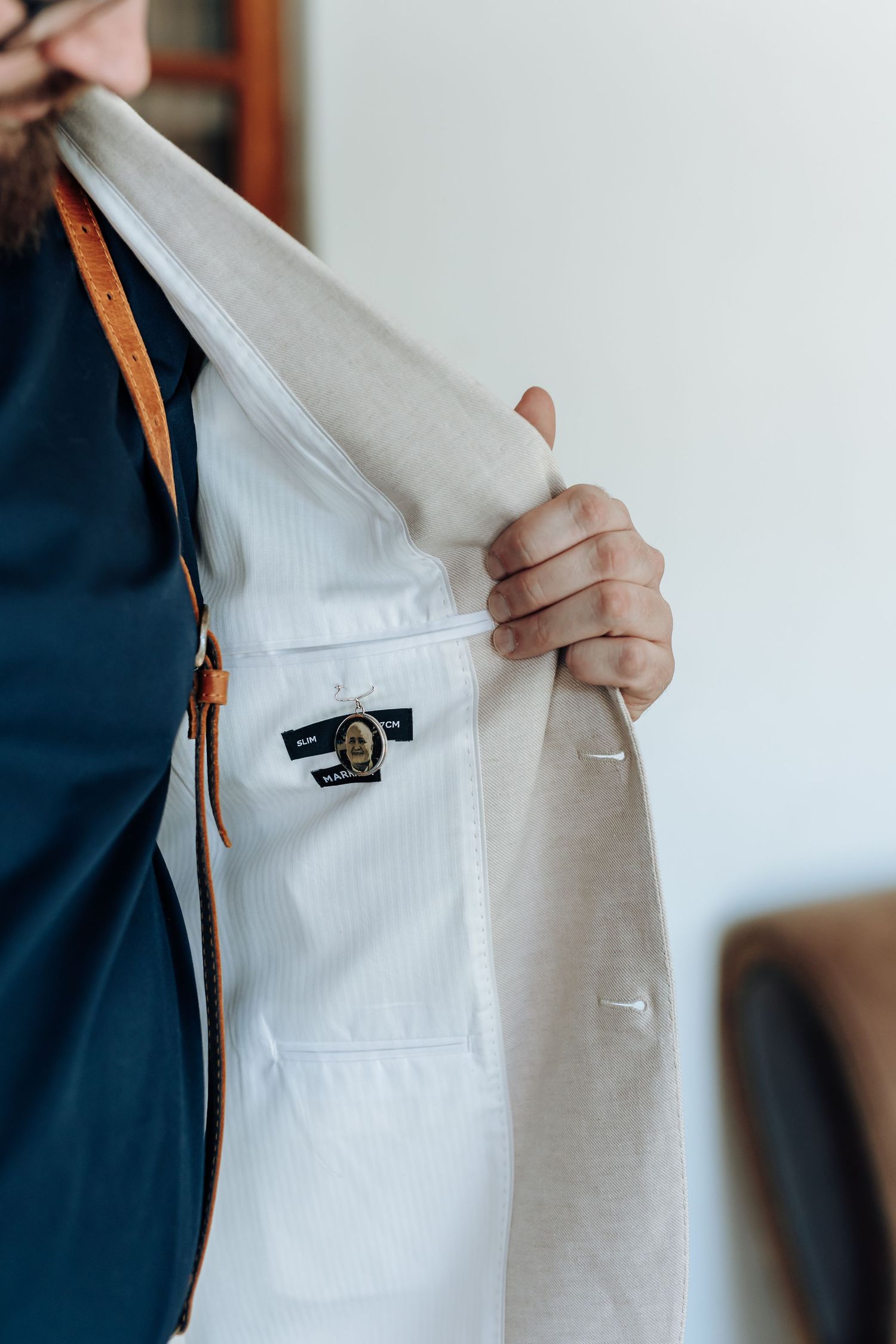 Close-up of someone adjusting a white lab coat with a small black logo patch on the breast pocket.