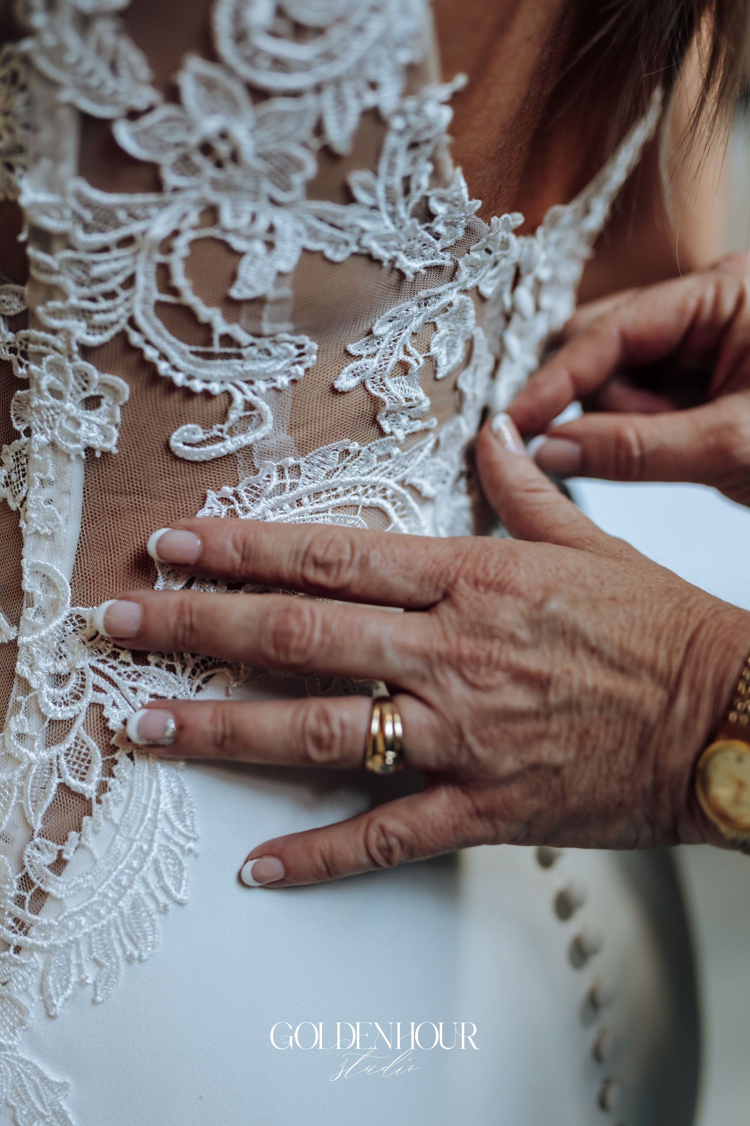 Close-up of hands with wedding rings against delicate white lace detail.