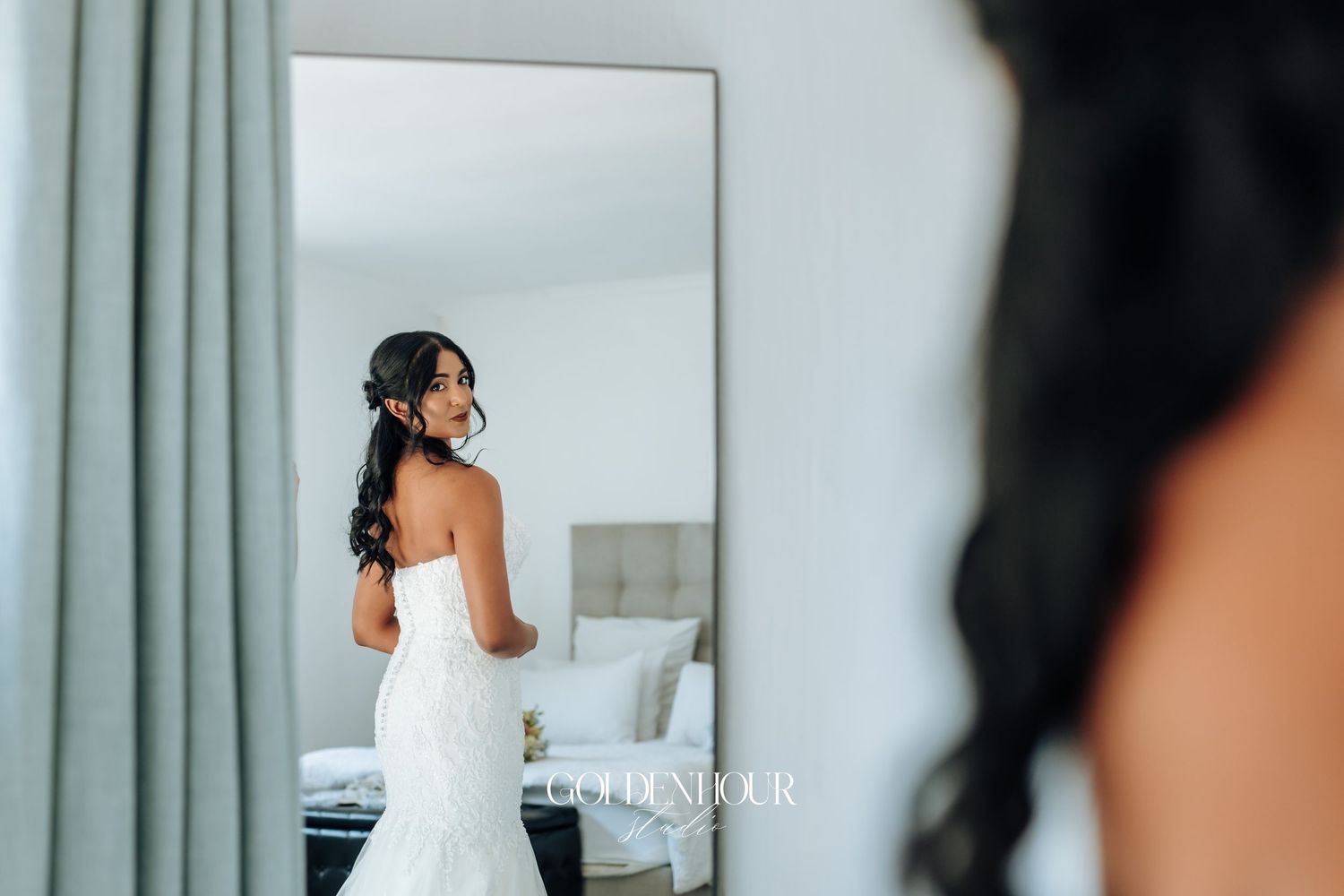 A wedding dress being fitted in a bright room with mint green curtains.