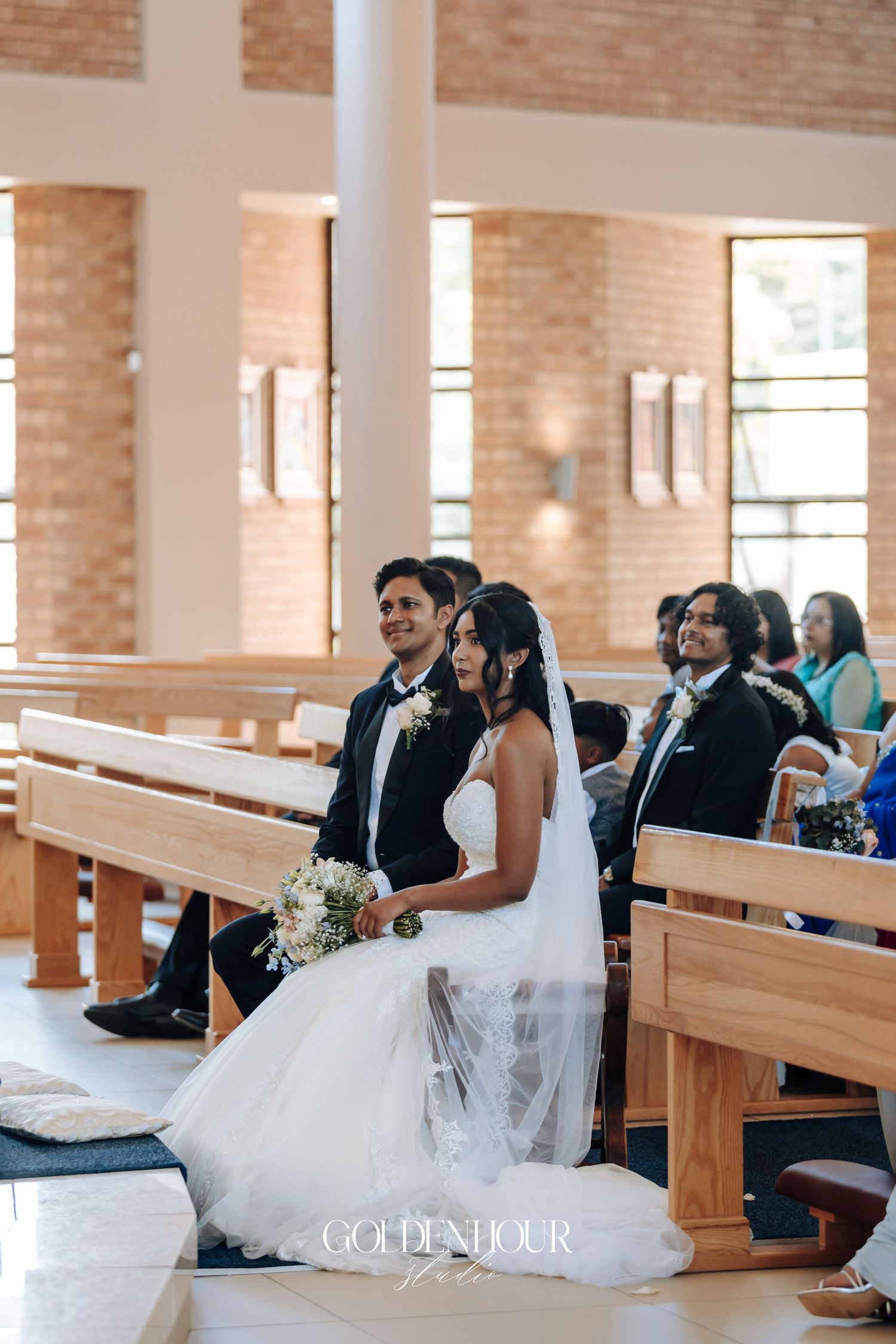 Wedding ceremony in modern church with exposed brick walls and wooden pews.