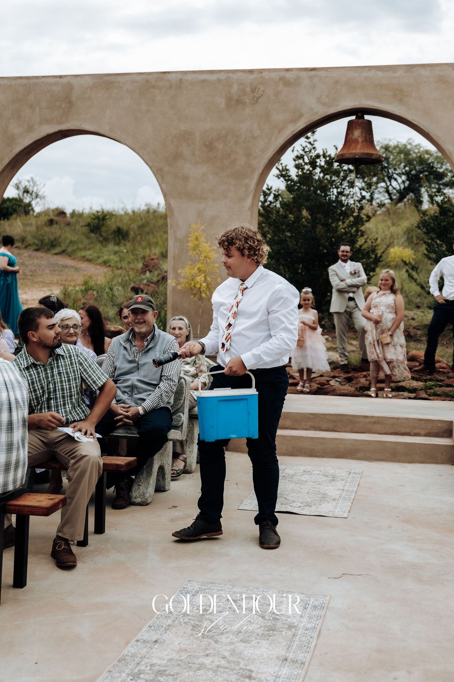 Candid moments of wedding guests relaxing under stone arches at an outdoor reception.