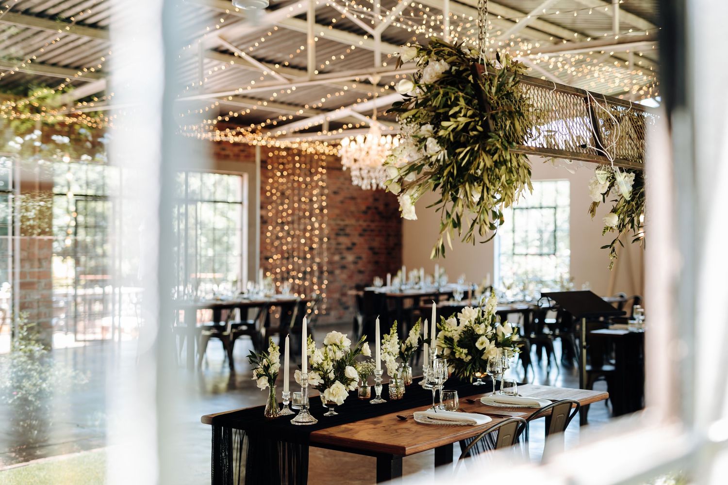 Modern industrial-style restaurant interior with exposed ceiling, wooden tables, and large windows letting in natural light.