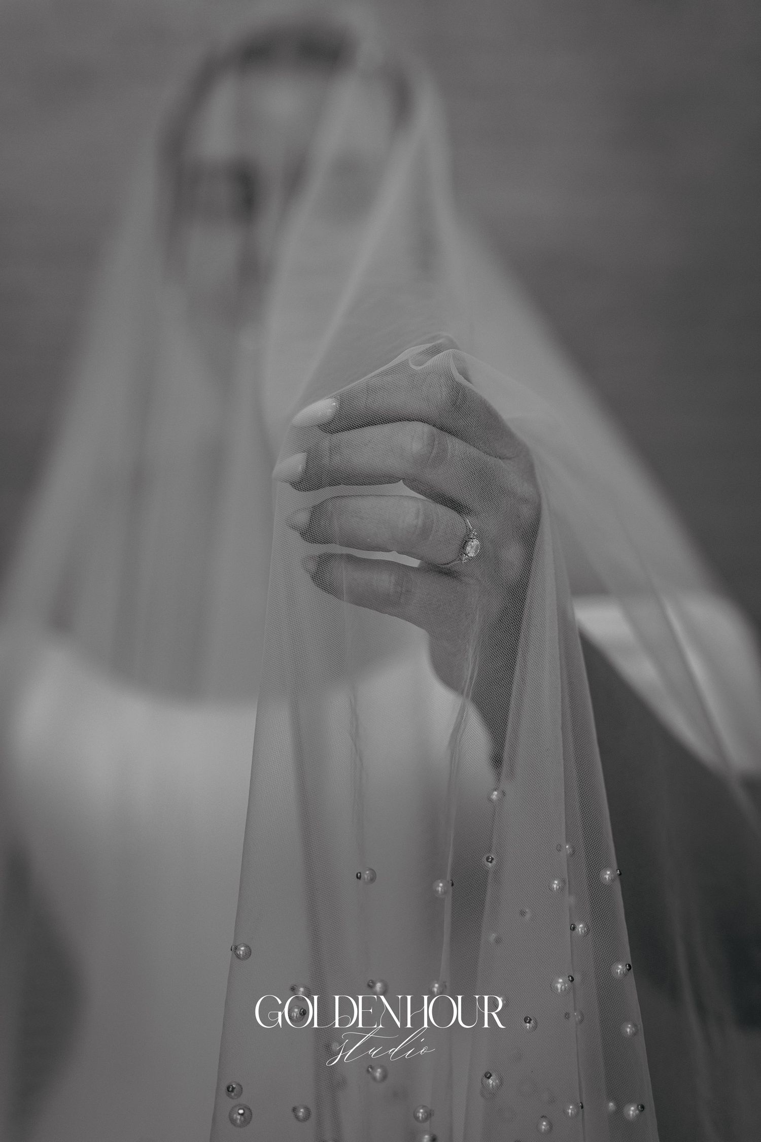 Delicate hands in soft focus reach upward with ethereal lighting and floating water droplets in a dreamy black and white scene.