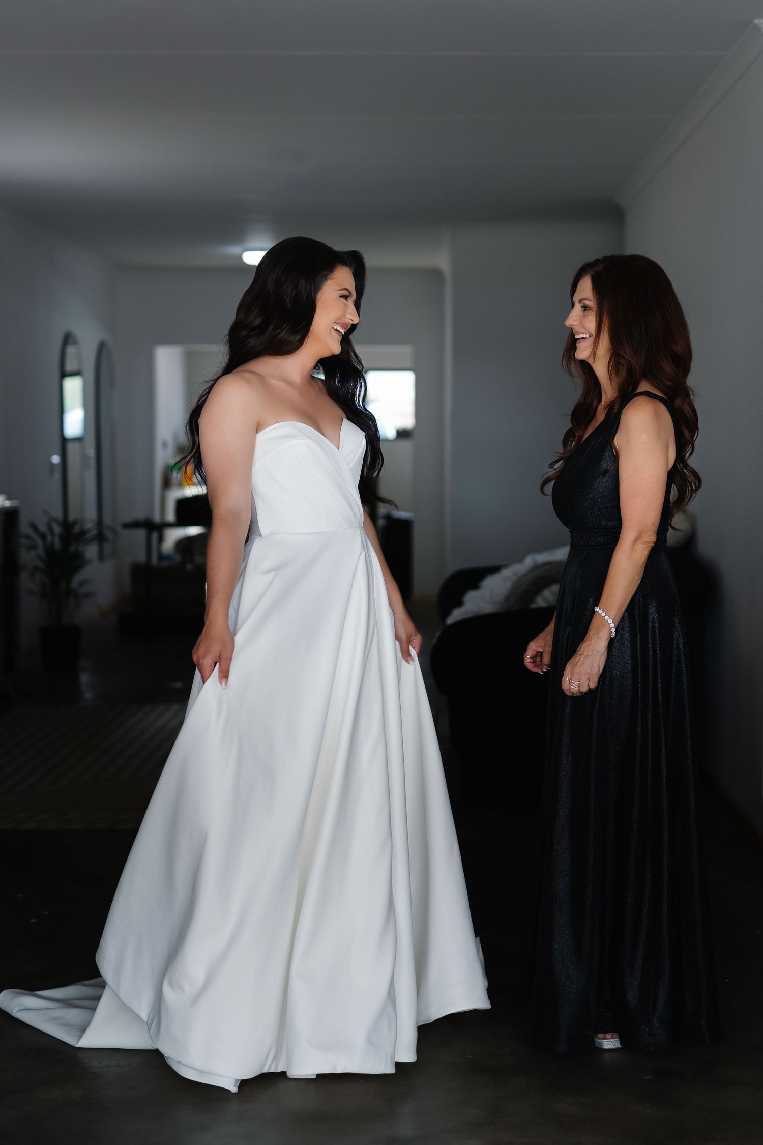 A series of wedding dress fitting photos showing a white gown against black bridesmaid dresses in an indoor setting.