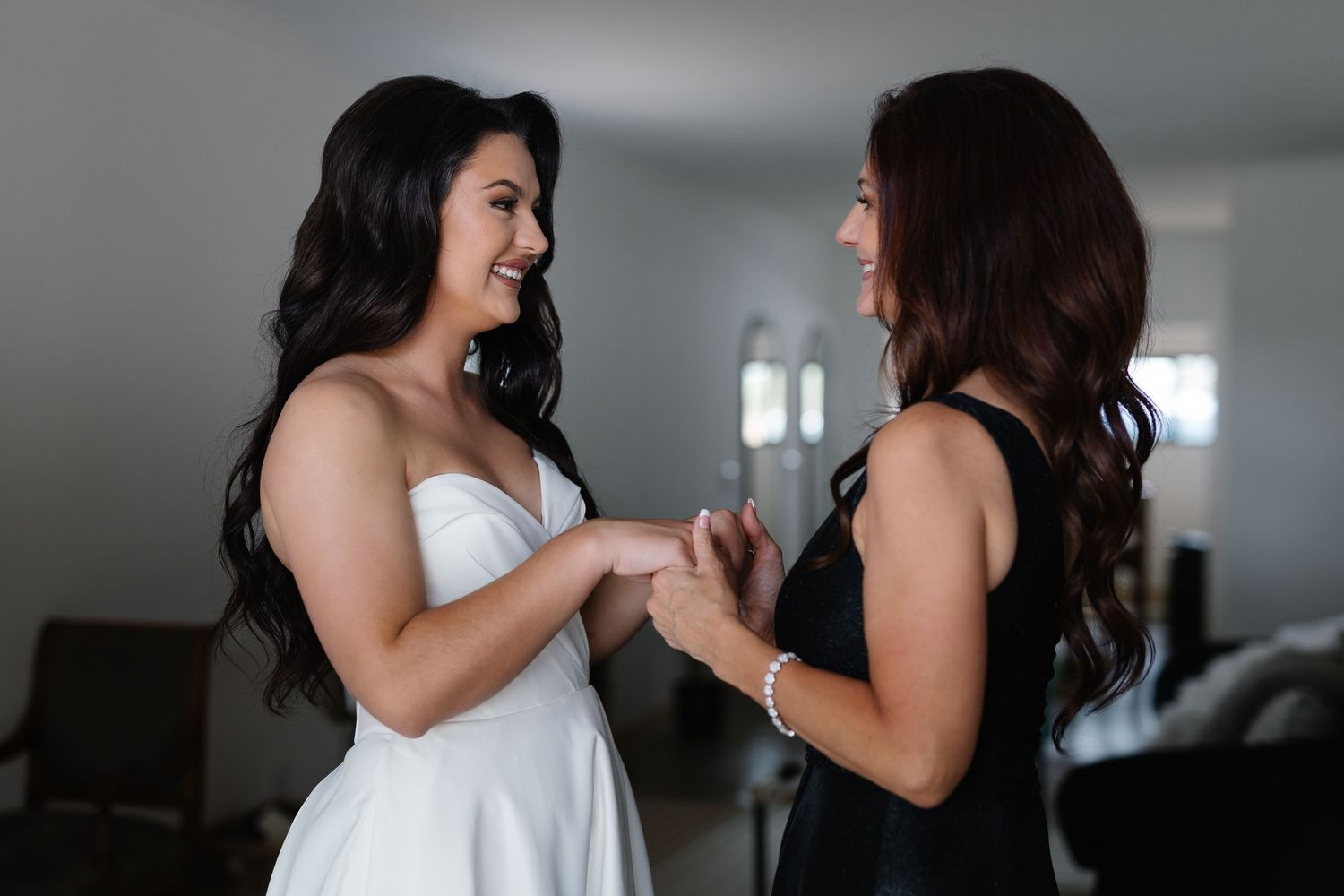 Two people in white dresses share joyful moments during a wedding celebration.