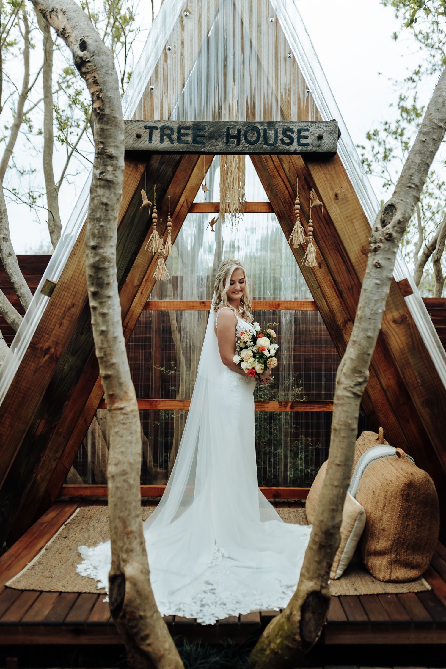 A series of photos showing a white wedding dress against a rustic treehouse backdrop with birch trees and wooden panels.