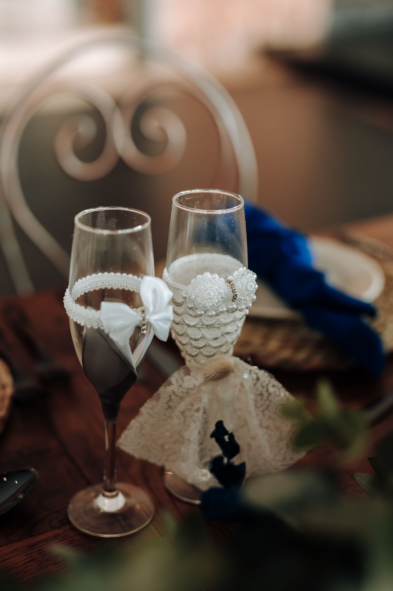 Decorated wedding champagne glasses with lace and ribbon details.