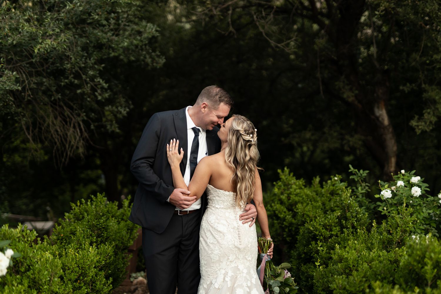Intimate wedding moment captured in a manicured garden setting.
