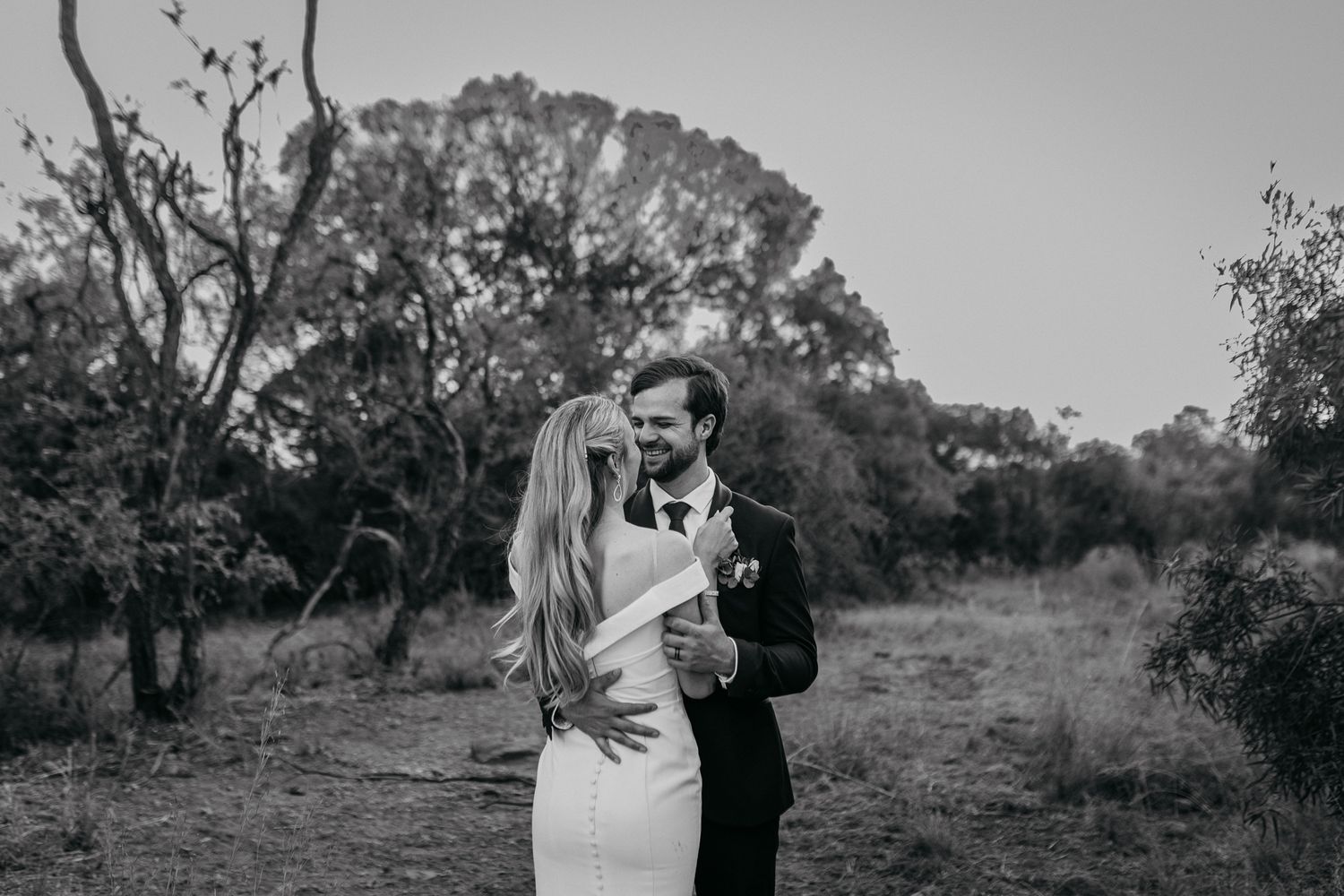 A black and white portrait of a couple sharing an intimate moment outdoors.