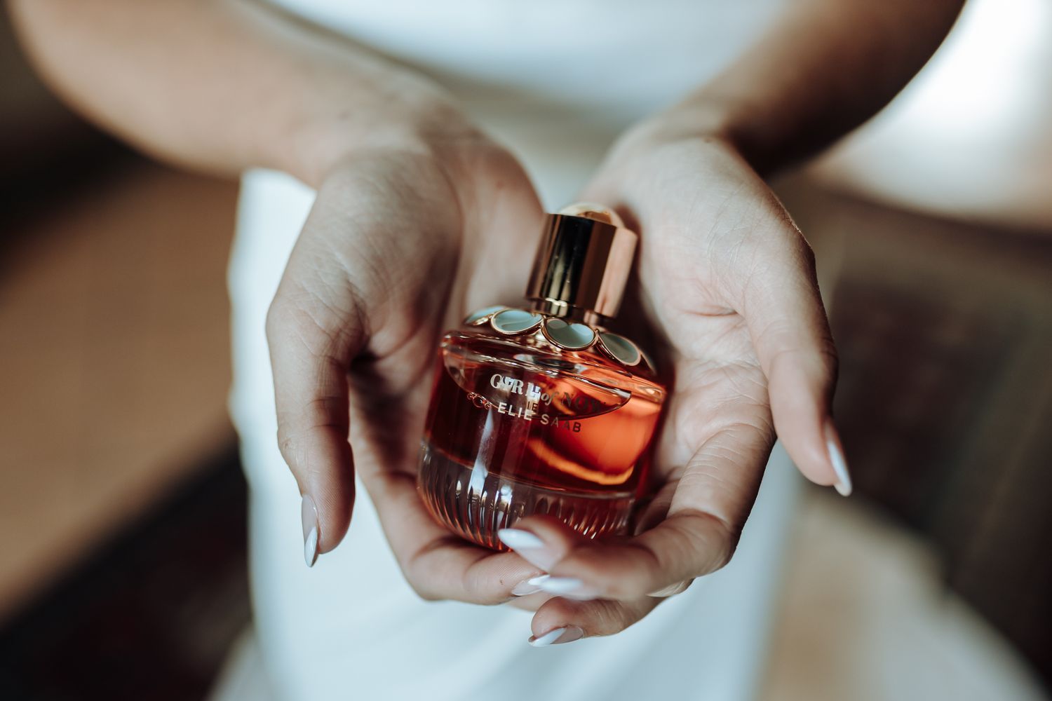 Hands holding an elegant perfume bottle in a soft focused shot.