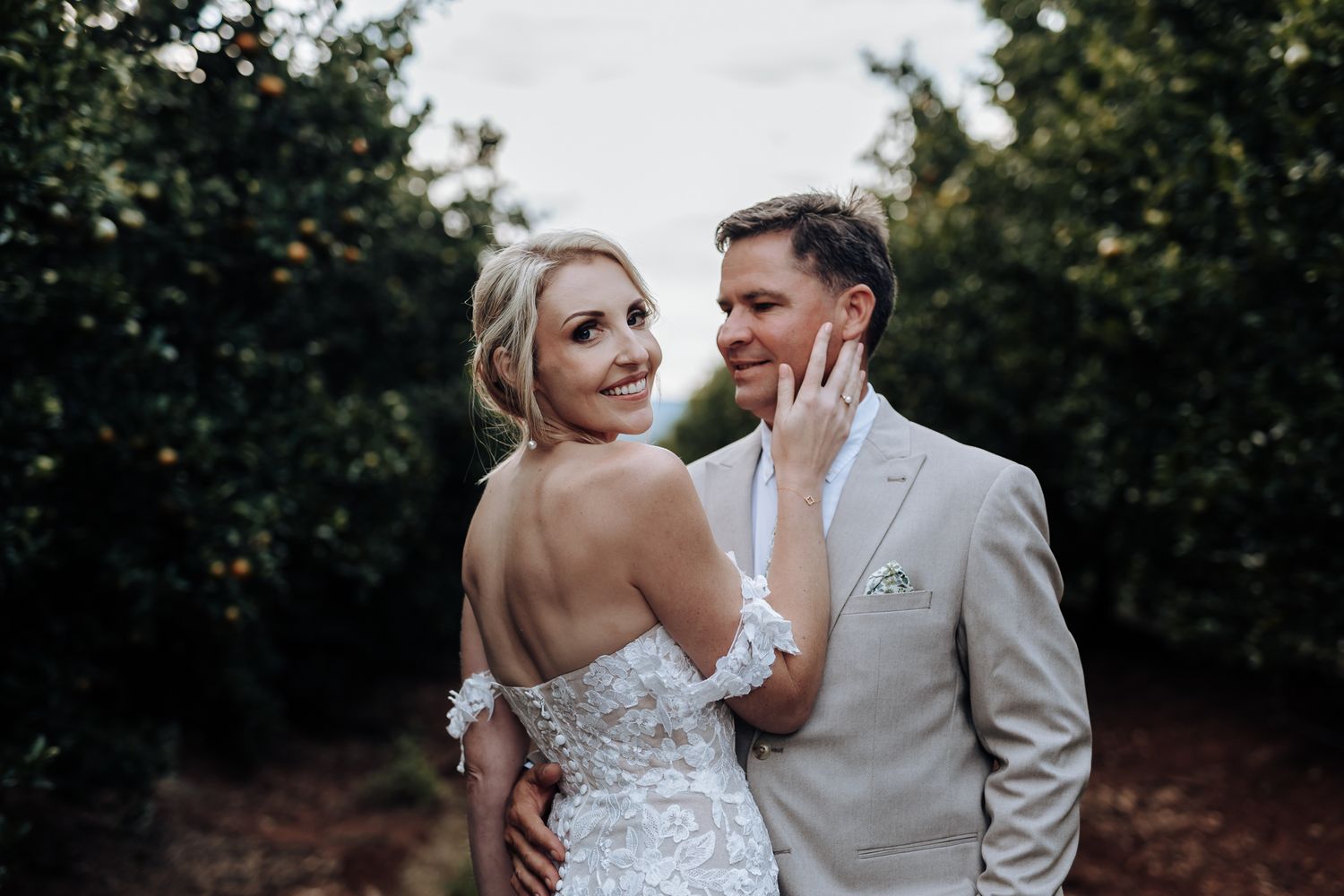 Intimate wedding moment captured between couple in orchard setting.