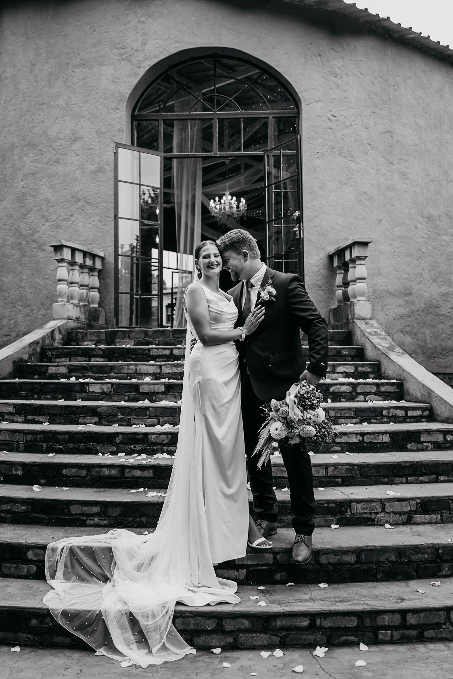 Black and white romantic wedding photos on stone steps showing couple in intimate poses and flowing wedding dress details.
