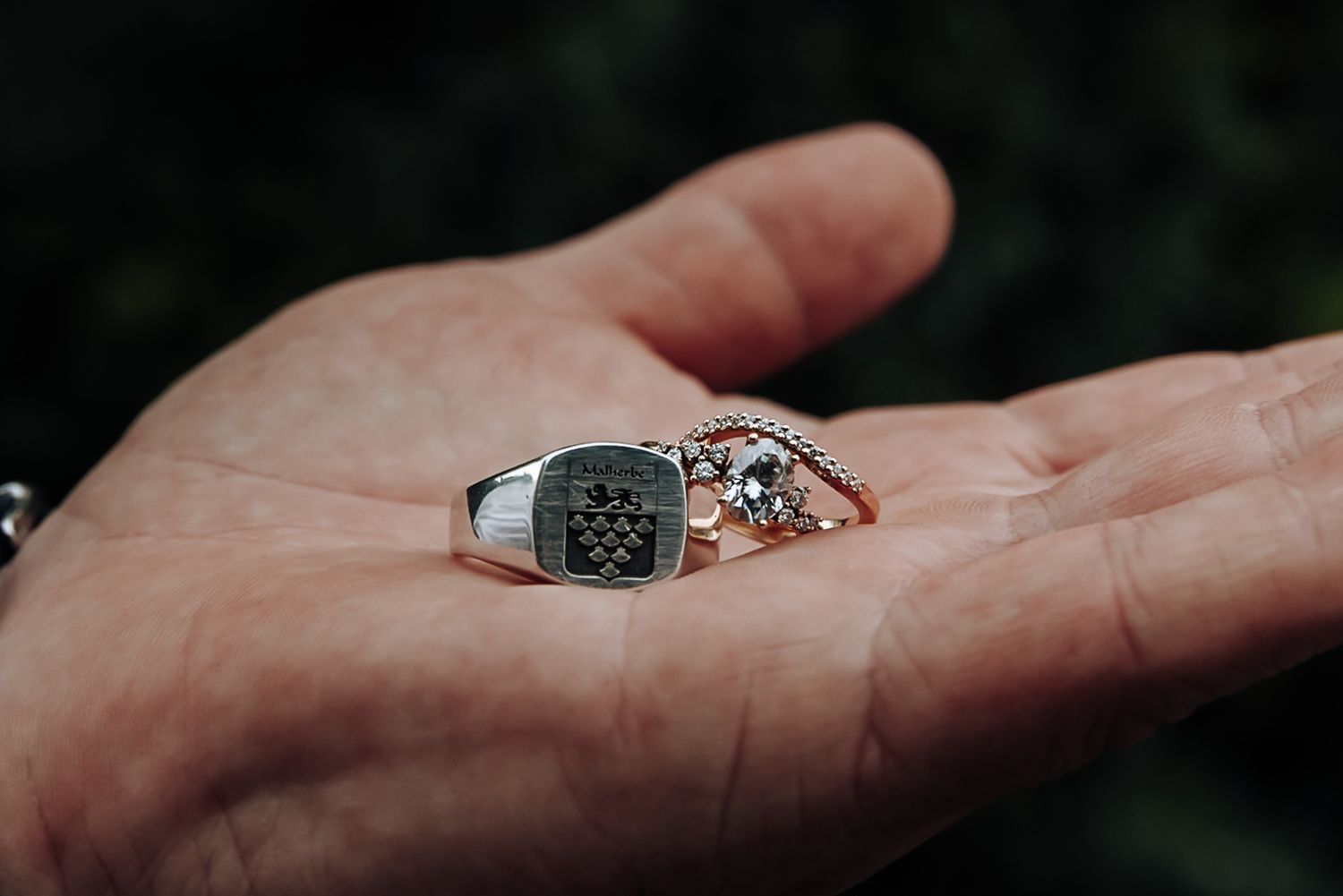 A silver and black ring rests in an outstretched palm against a dark blurred background.