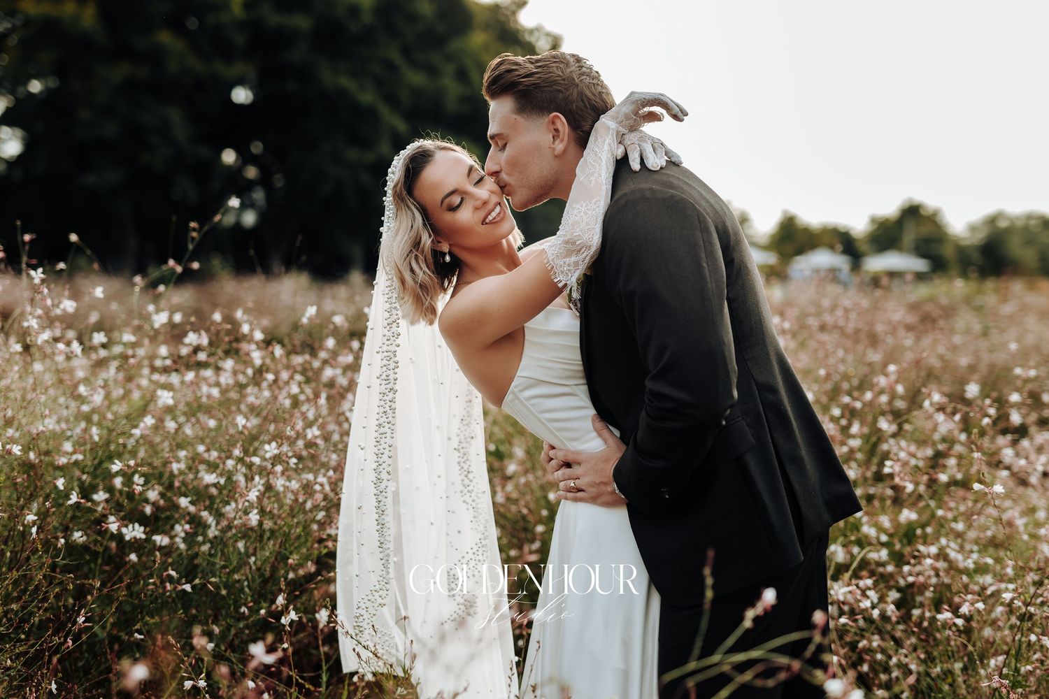 Wedding couple shares intimate moment in field of delicate white flowers.