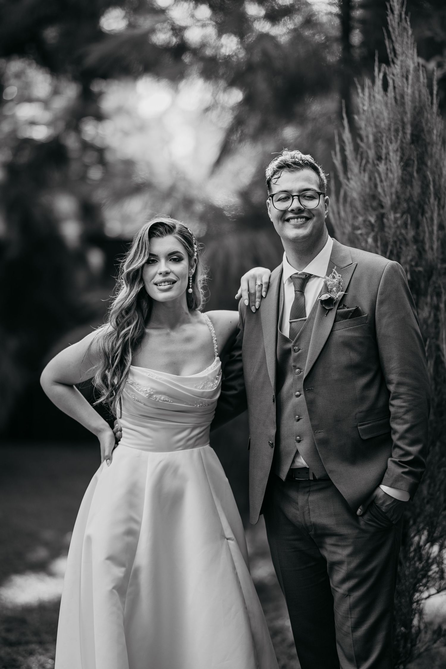 A romantic black and white wedding portrait captured in a garden setting.