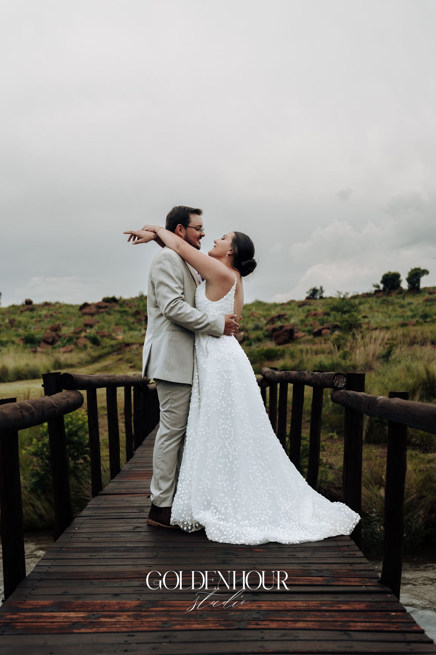 Newlyweds sharing a romantic moment on a wooden deck overlooking natural landscape.