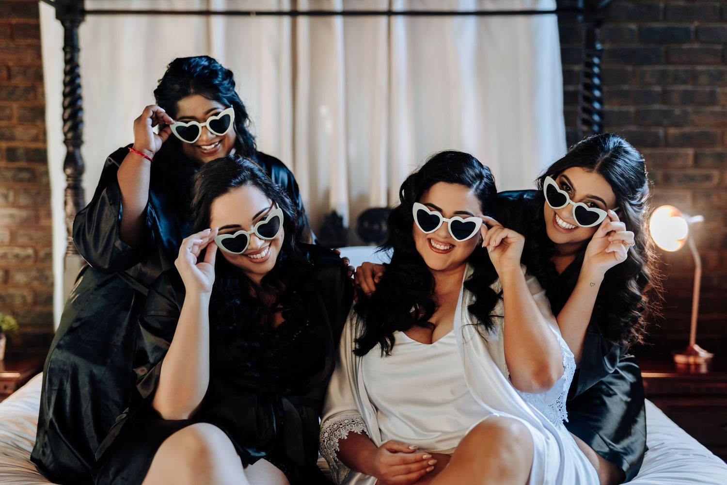 Group wearing matching sunglasses pose playfully together during wedding celebration.
