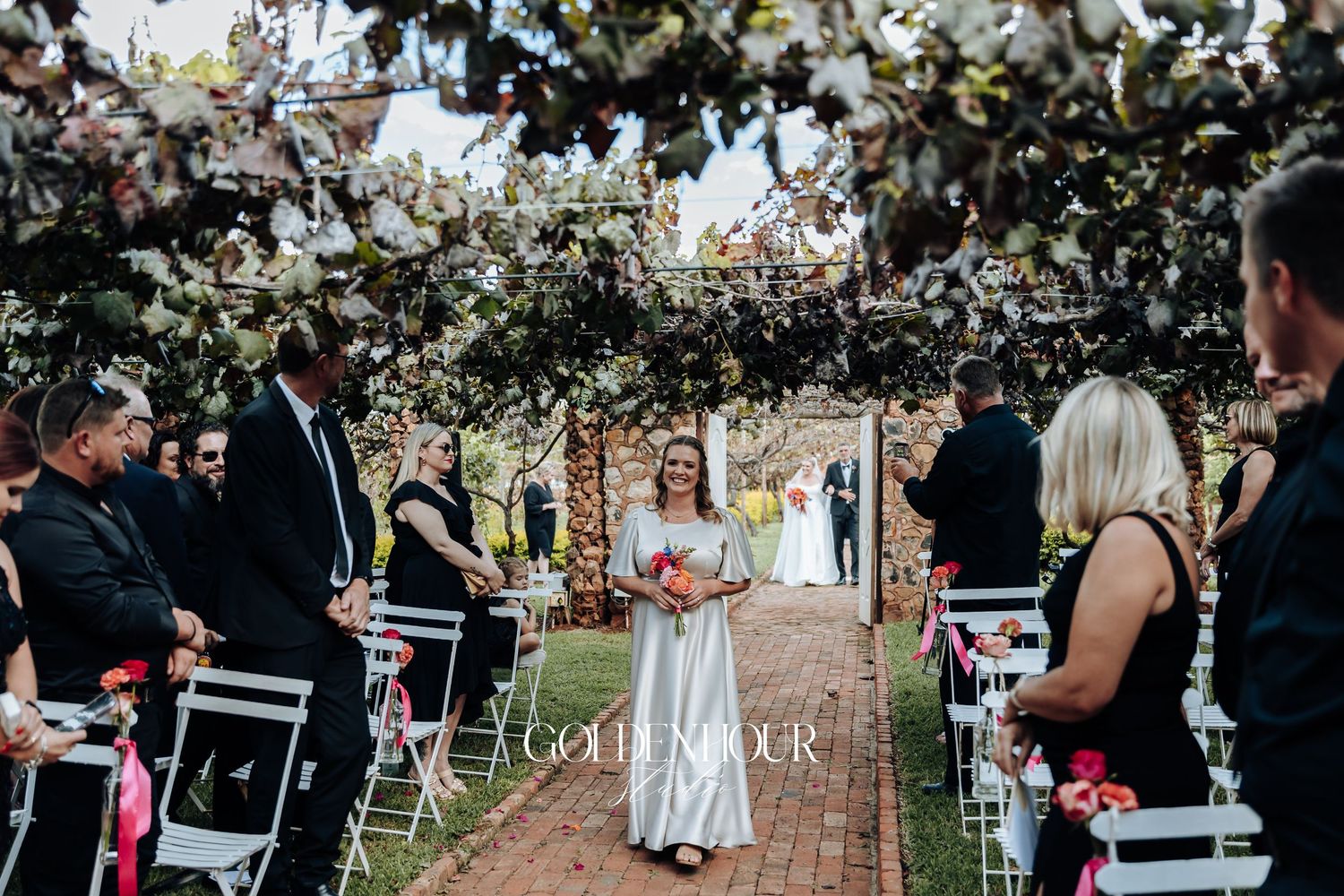 Outdoor wedding ceremony setup with white chairs and floral decorations under blooming cherry blossom trees.