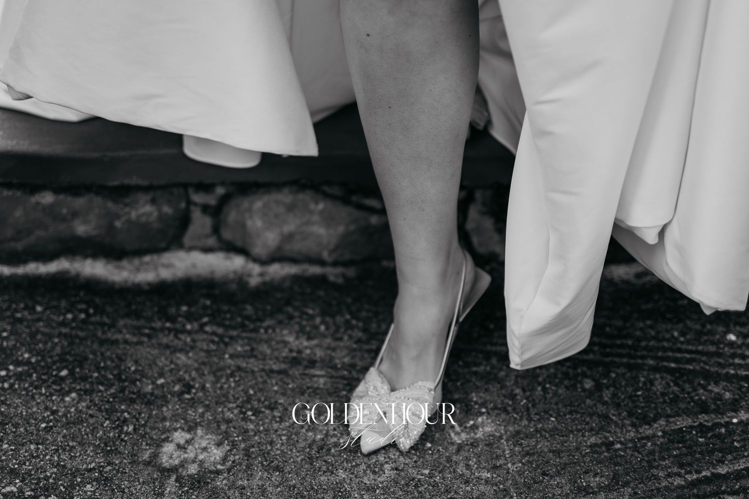 Black and white wedding photo showing feet dancing together on a rustic wooden floor.