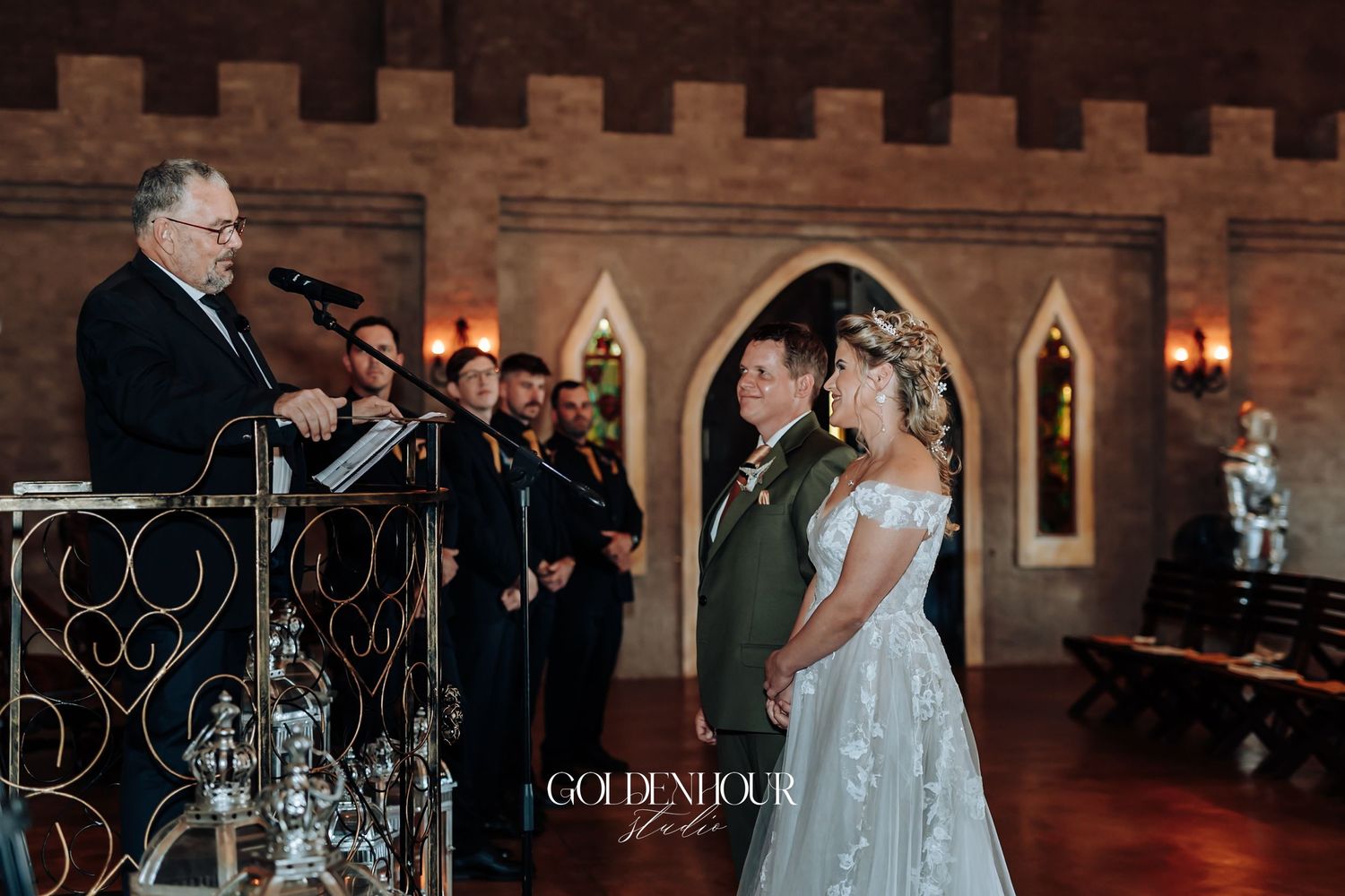 Bride and groom exchanging vows at castle wedding ceremony with officiant and choir in background.