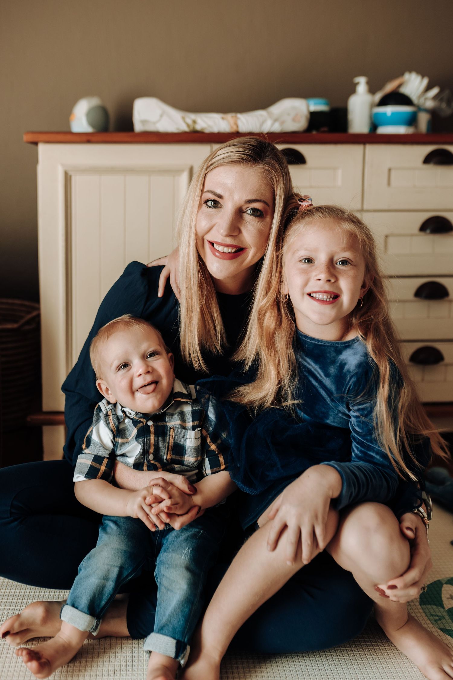 Family sitting together on couch in warm natural lighting, sharing loving embraces and joyful moments.