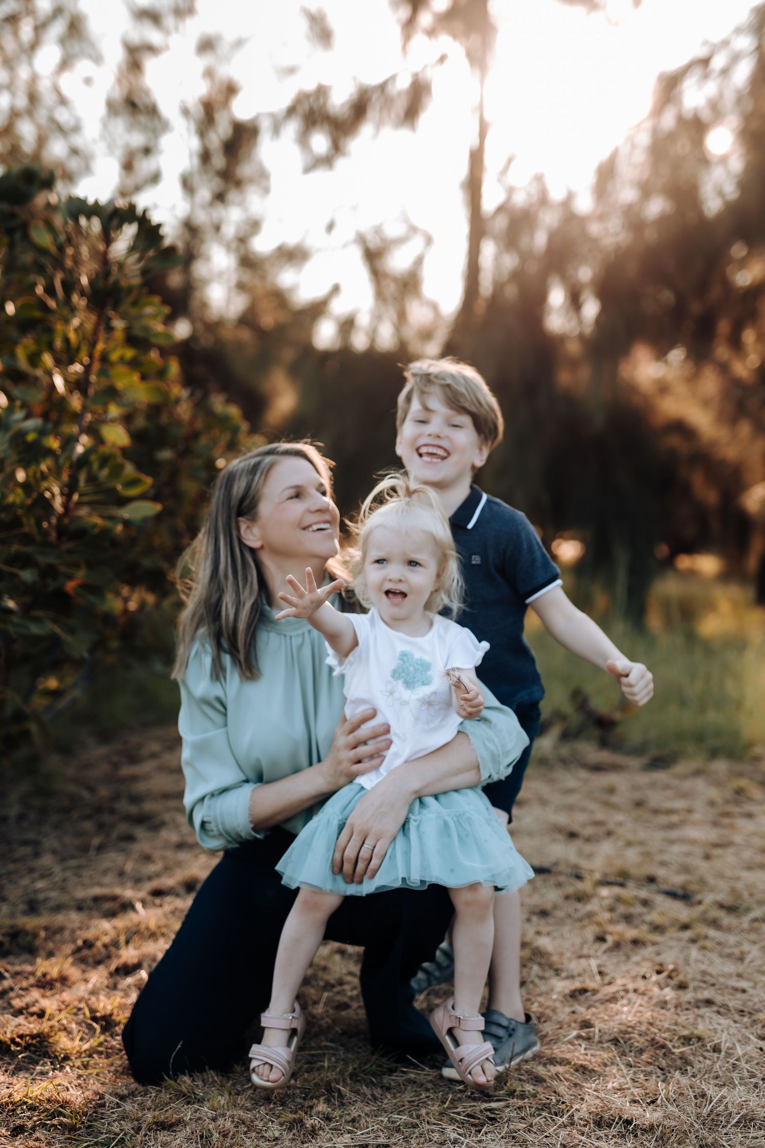 Family enjoying playful moments together during golden hour photography session in a natural outdoor setting.