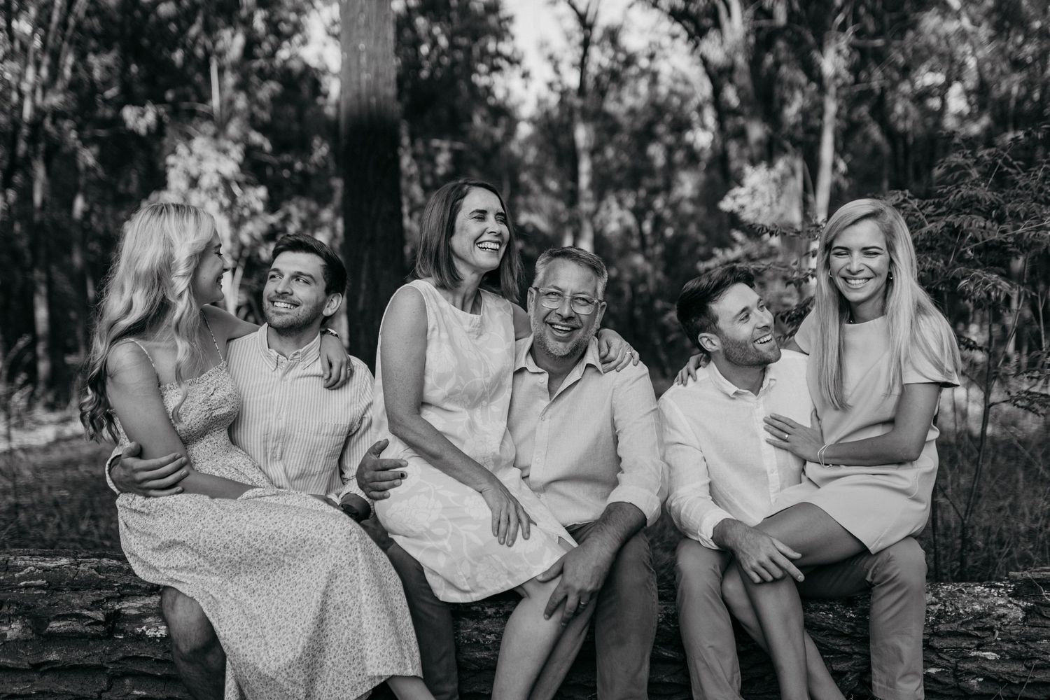 Black and white photo series showing joyful moments of people sitting and laughing together outdoors.