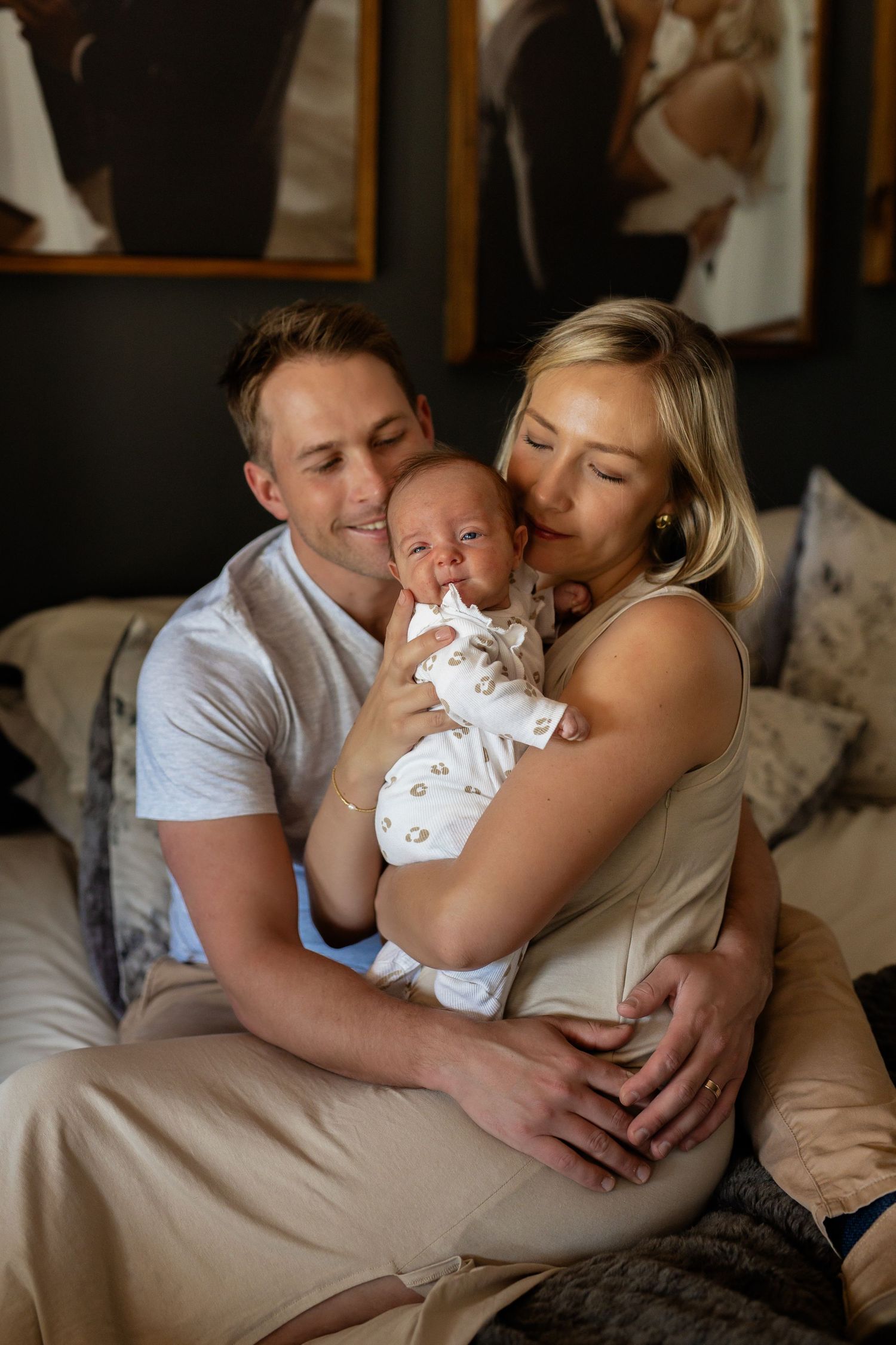 A family shares tender moments together while relaxing on a beige couch in a cozy indoor setting.