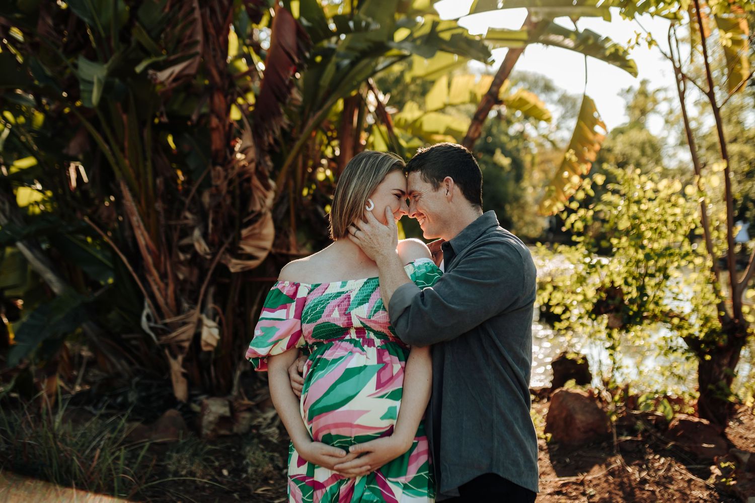 A couple shares a romantic moment together in a lush garden setting during golden hour sunlight.