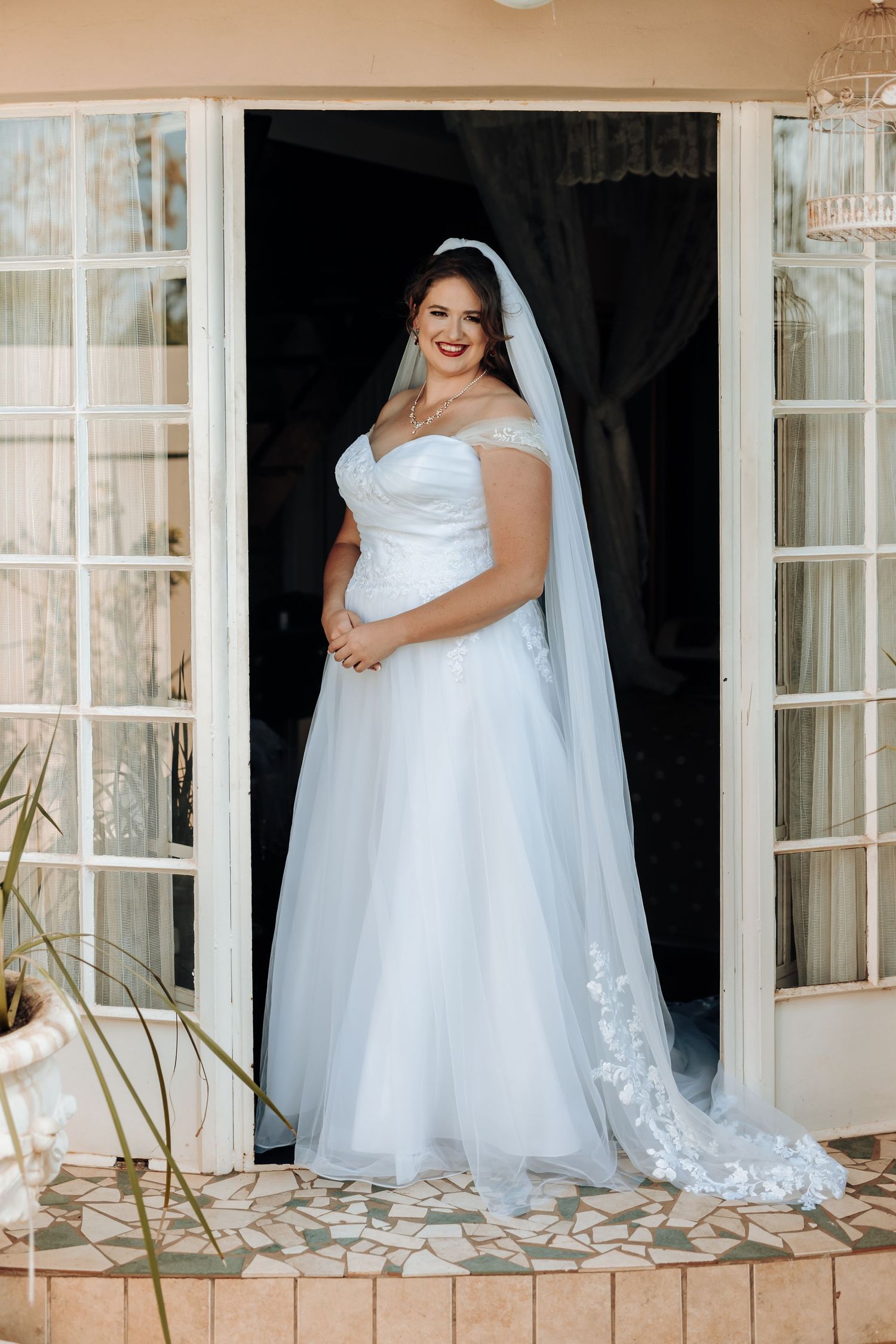 A radiant bride poses in a doorway wearing a classic ballgown with flowing veil.