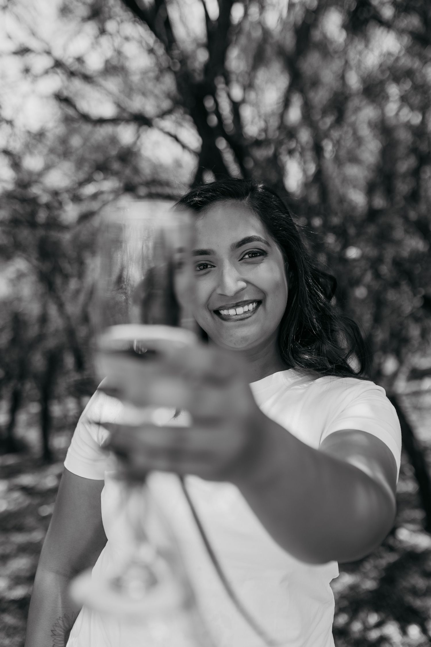 Black and white portrait showing raised champagne glass in outdoor setting.