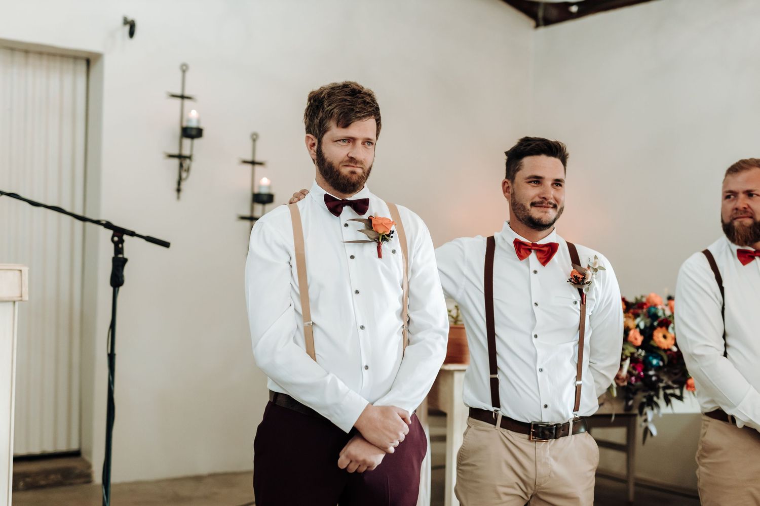 Groomsmen in white shirts with suspenders and red bowties stand at altar.