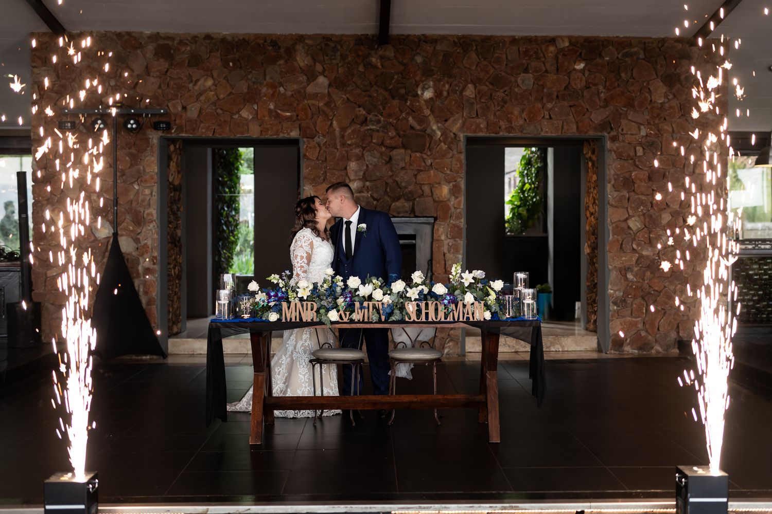Wedding reception table setup with sparkler fountains and elegant decor in rustic venue.
