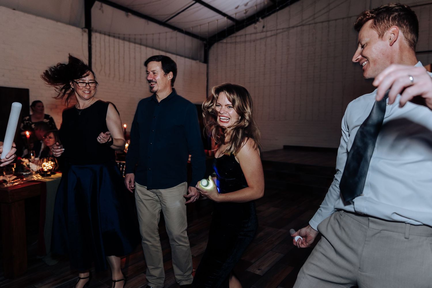 Group of friends dancing and celebrating at an indoor wedding reception party event.