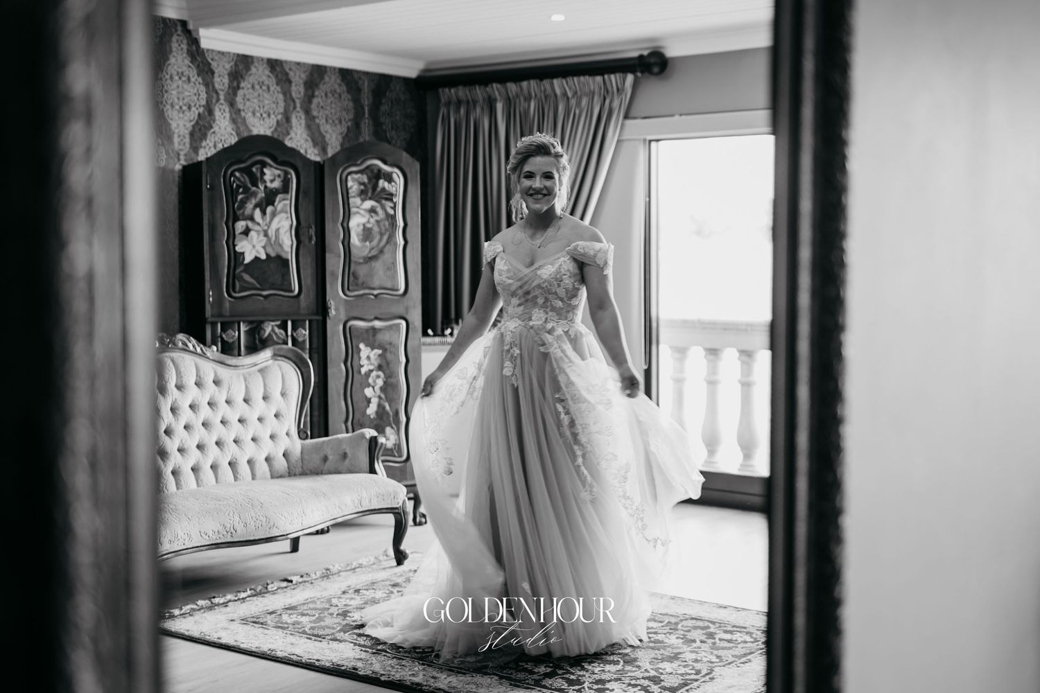 Black and white mirror reflection of a bride in a flowing ball gown wedding dress in an elegant room.