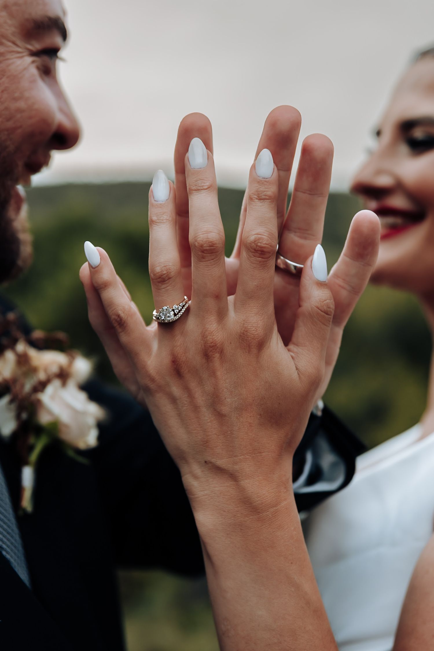 Close-up sequence of hands showing off wedding rings against a blurred outdoor background.