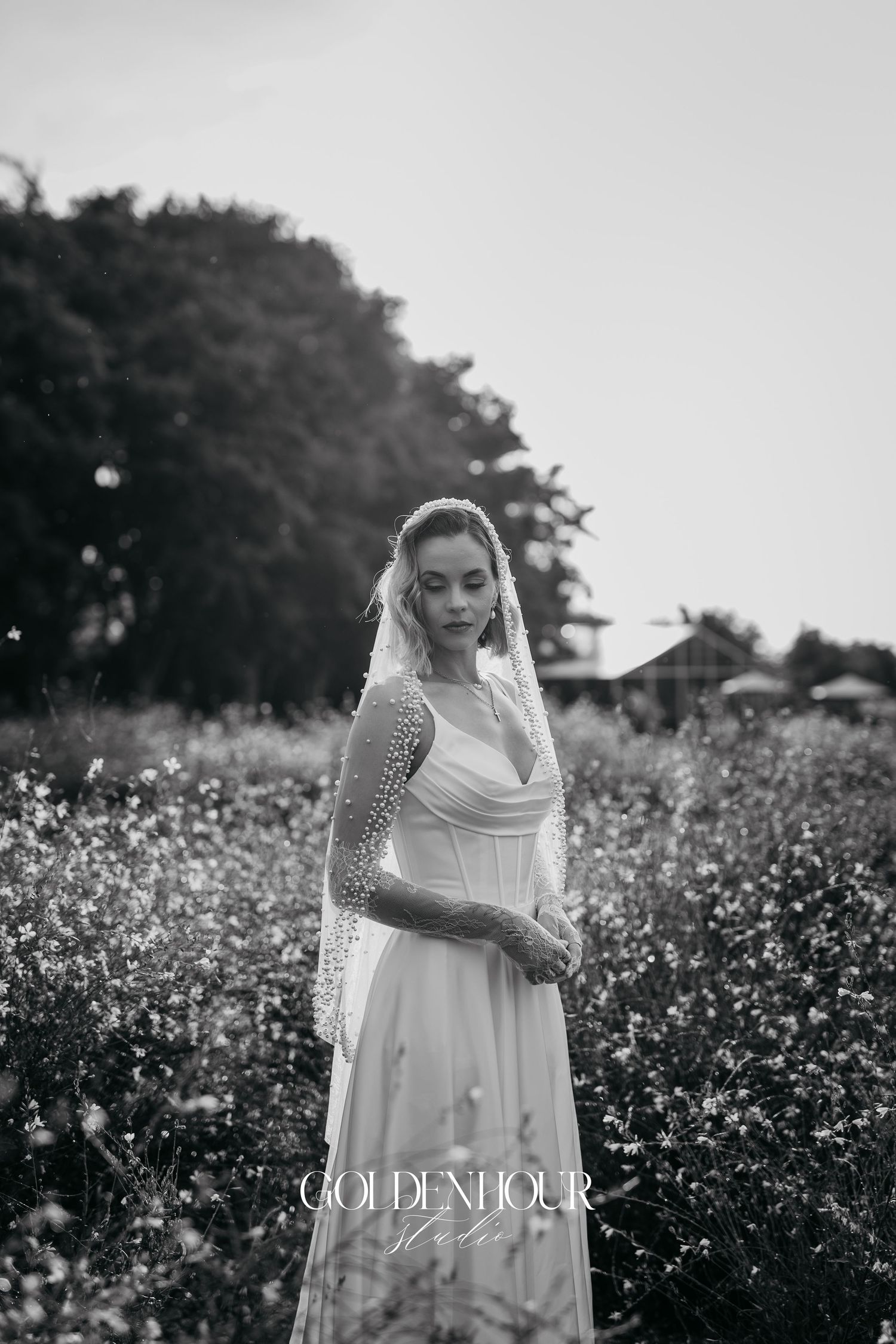 Artistic black and white bridal portraits in a flowering field with soft natural lighting.