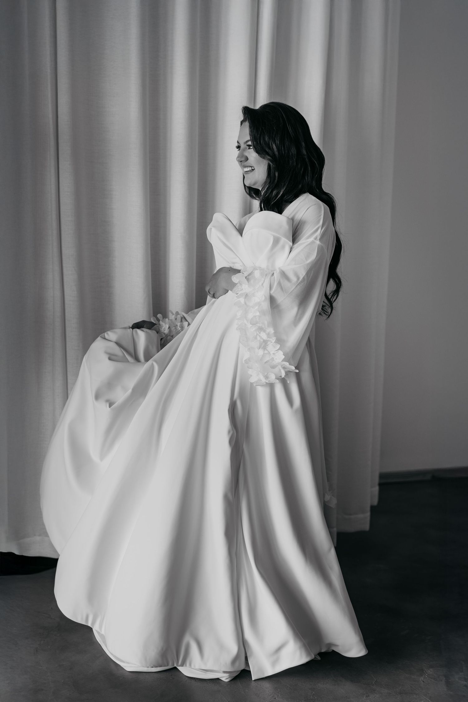 A black and white photo series showing flowing white fabric in motion against a light curtained background.